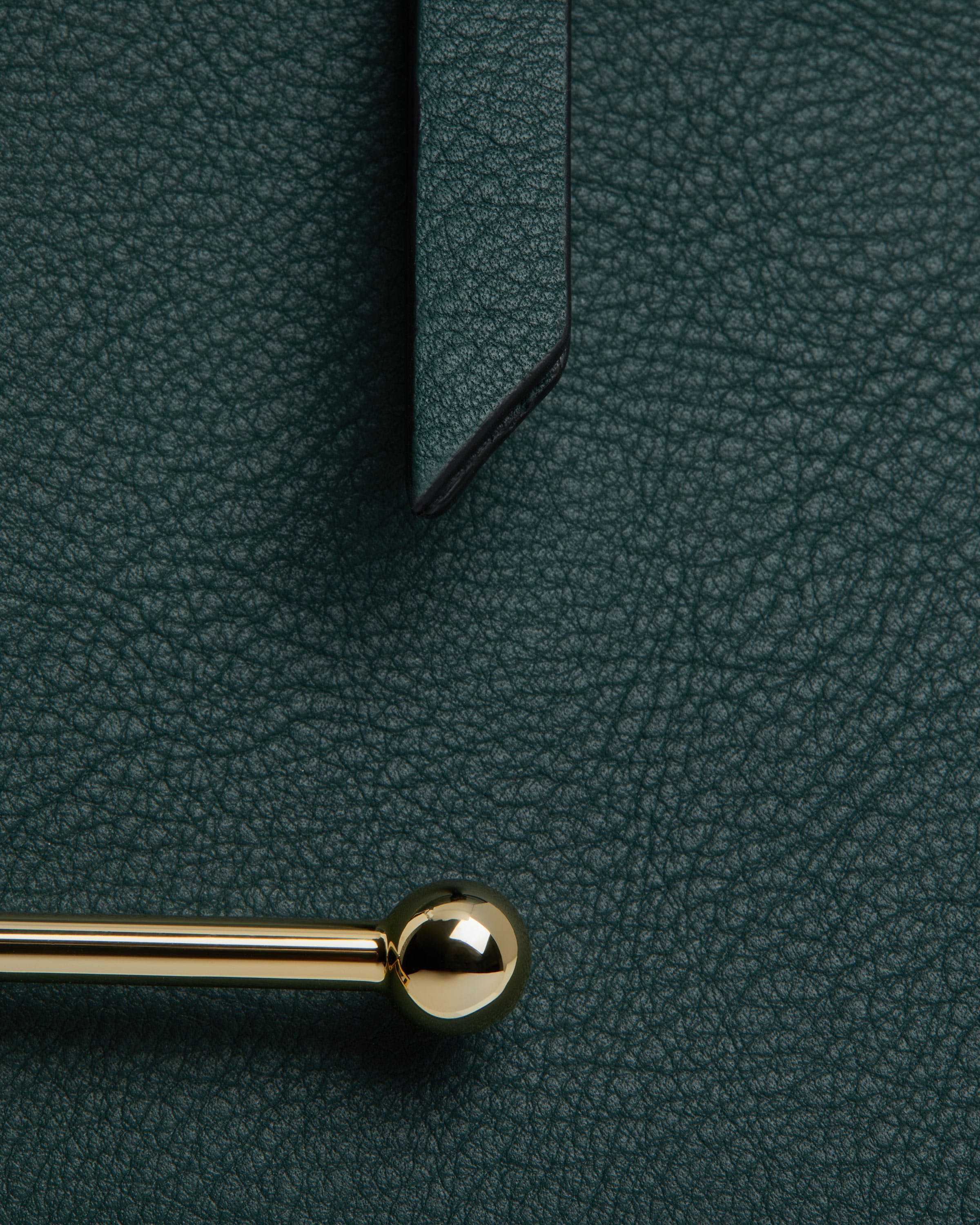 A close up of a green leather surface with a gold handle