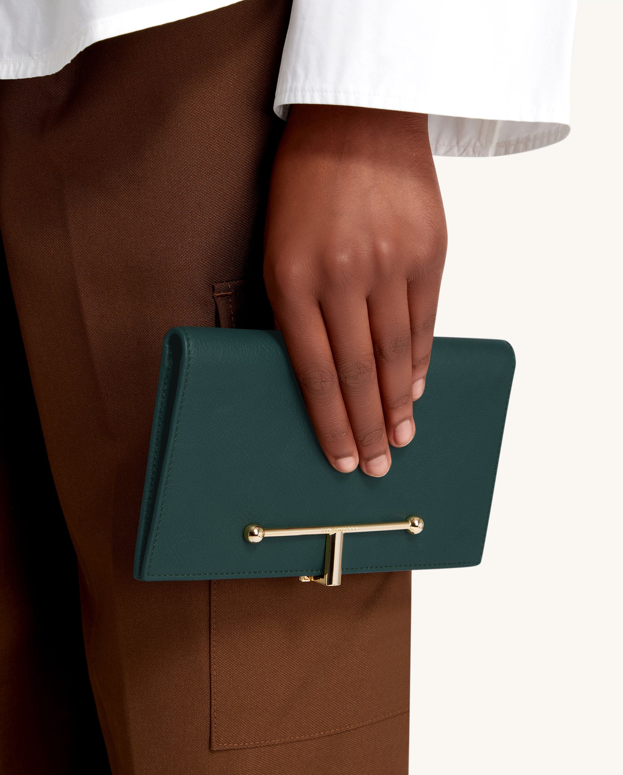 A woman's hand holding a green purse