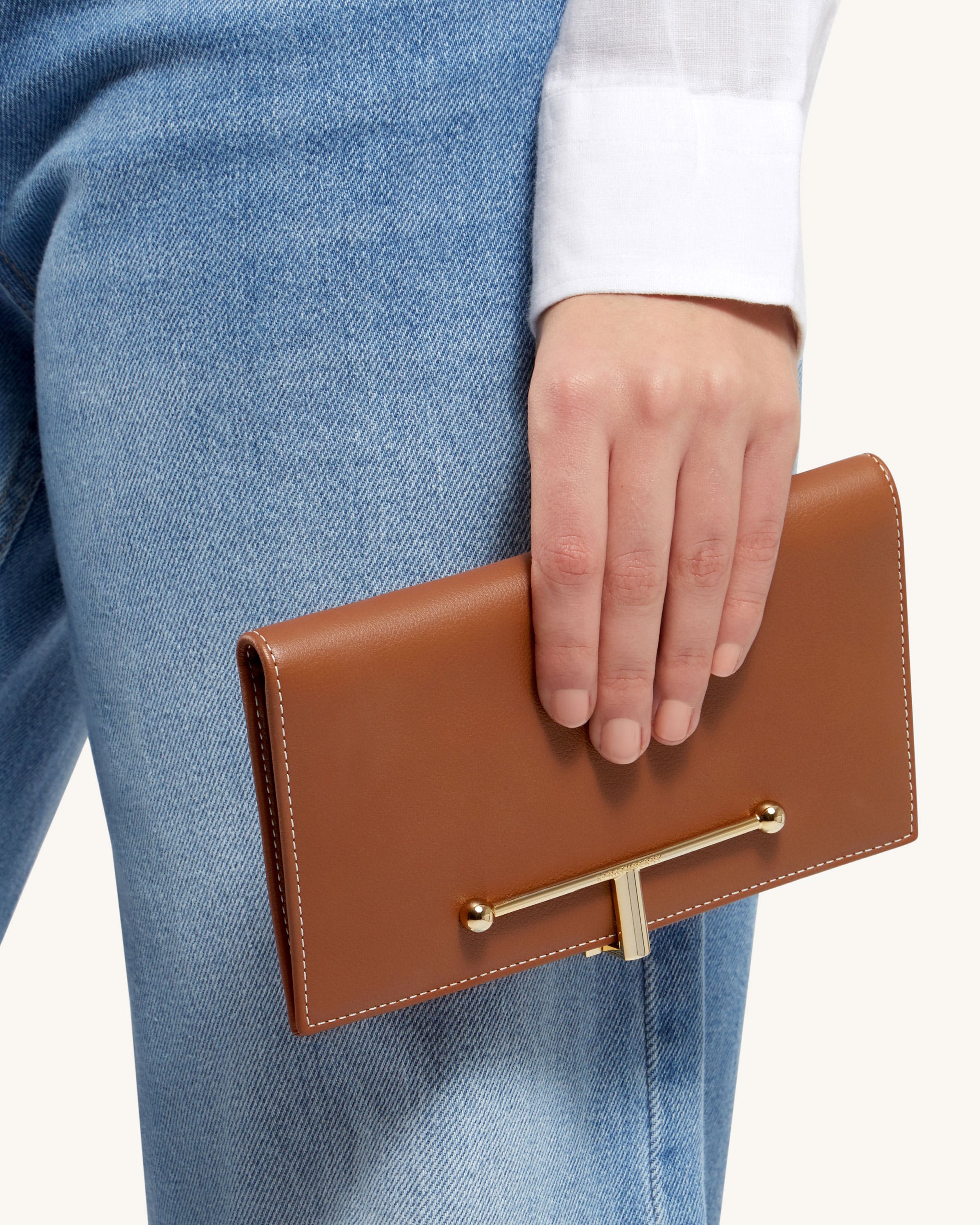 A person holding a brown leather purse