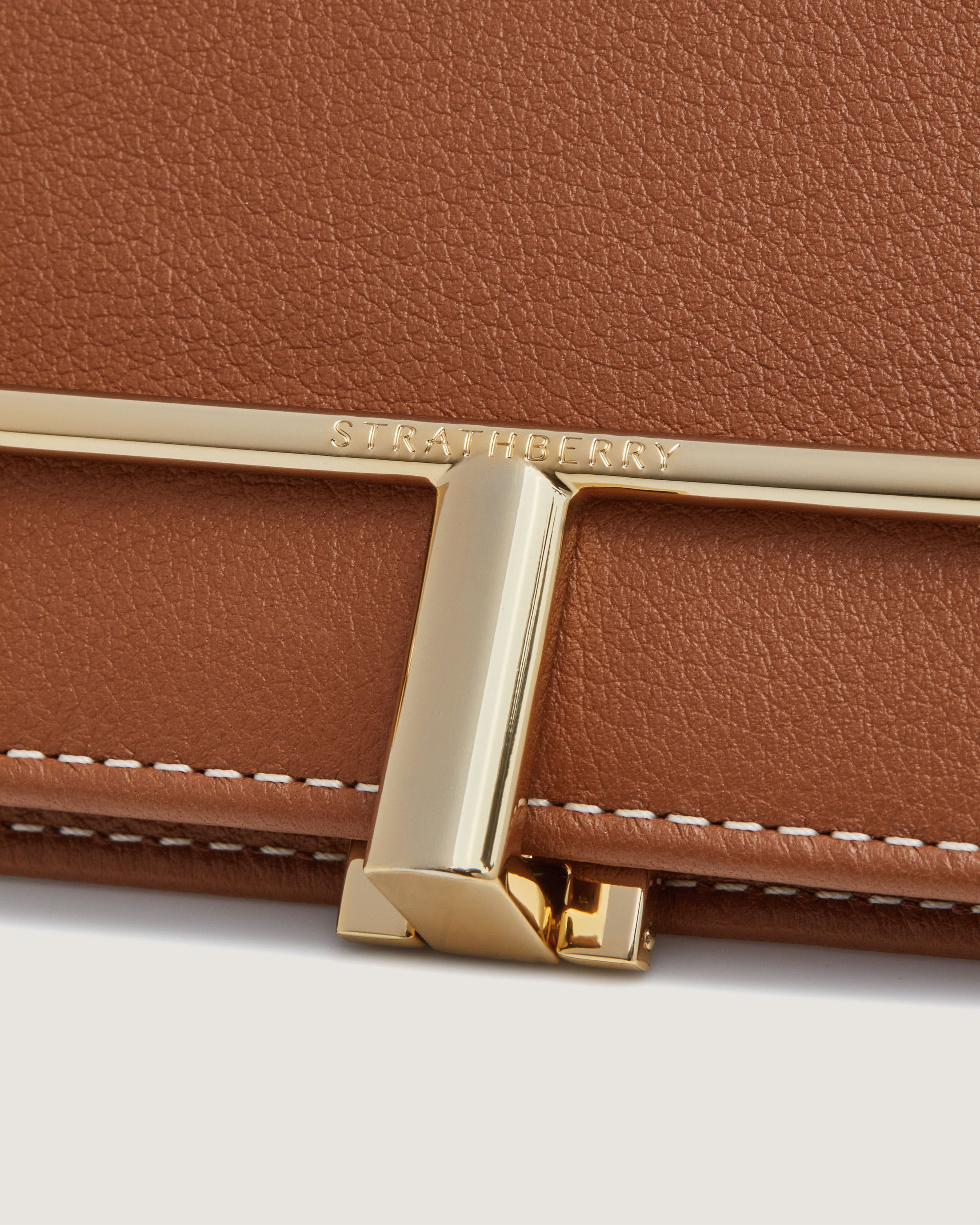 A close up of a brown purse on a white surface