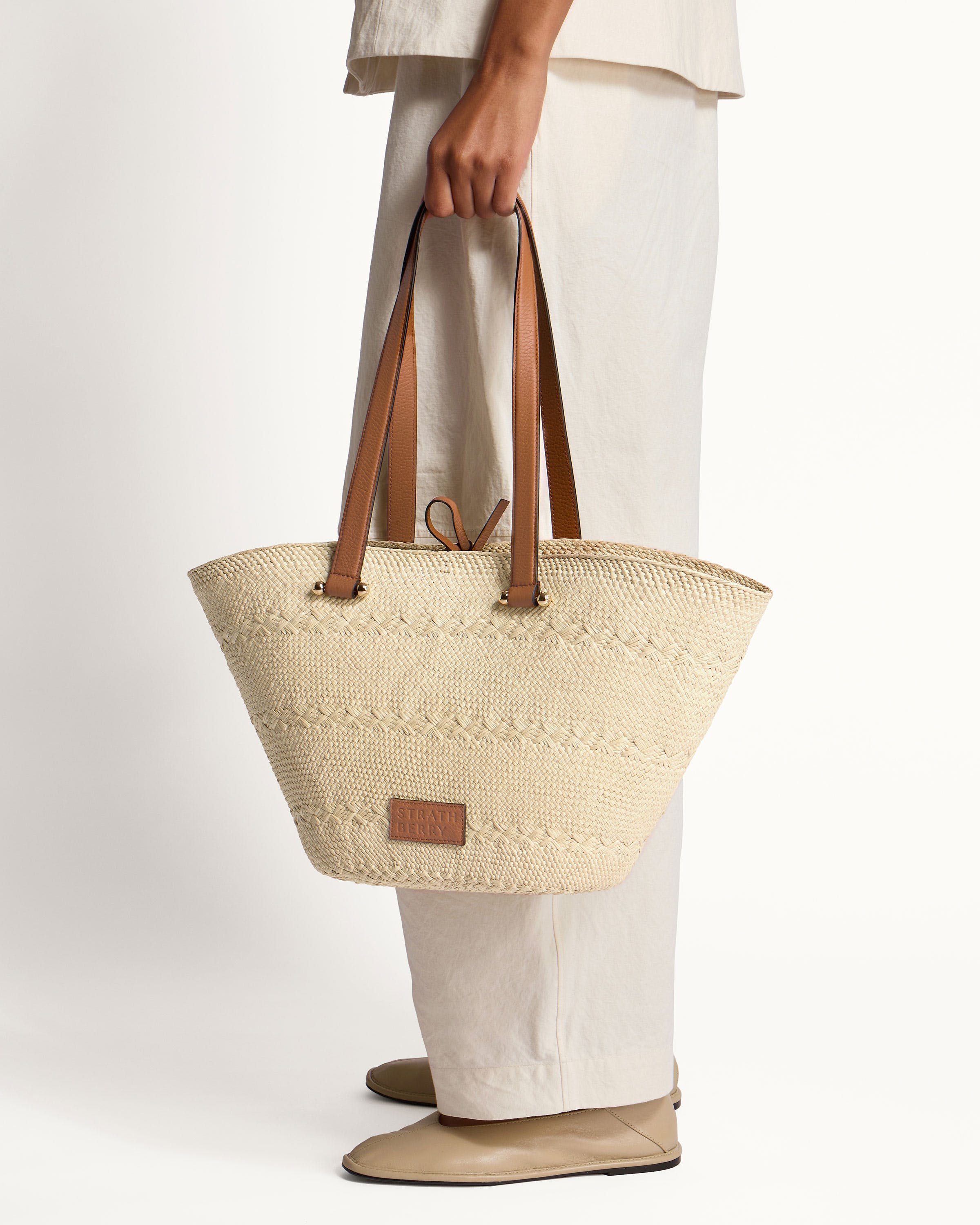 A woman holding a white bag with brown handles