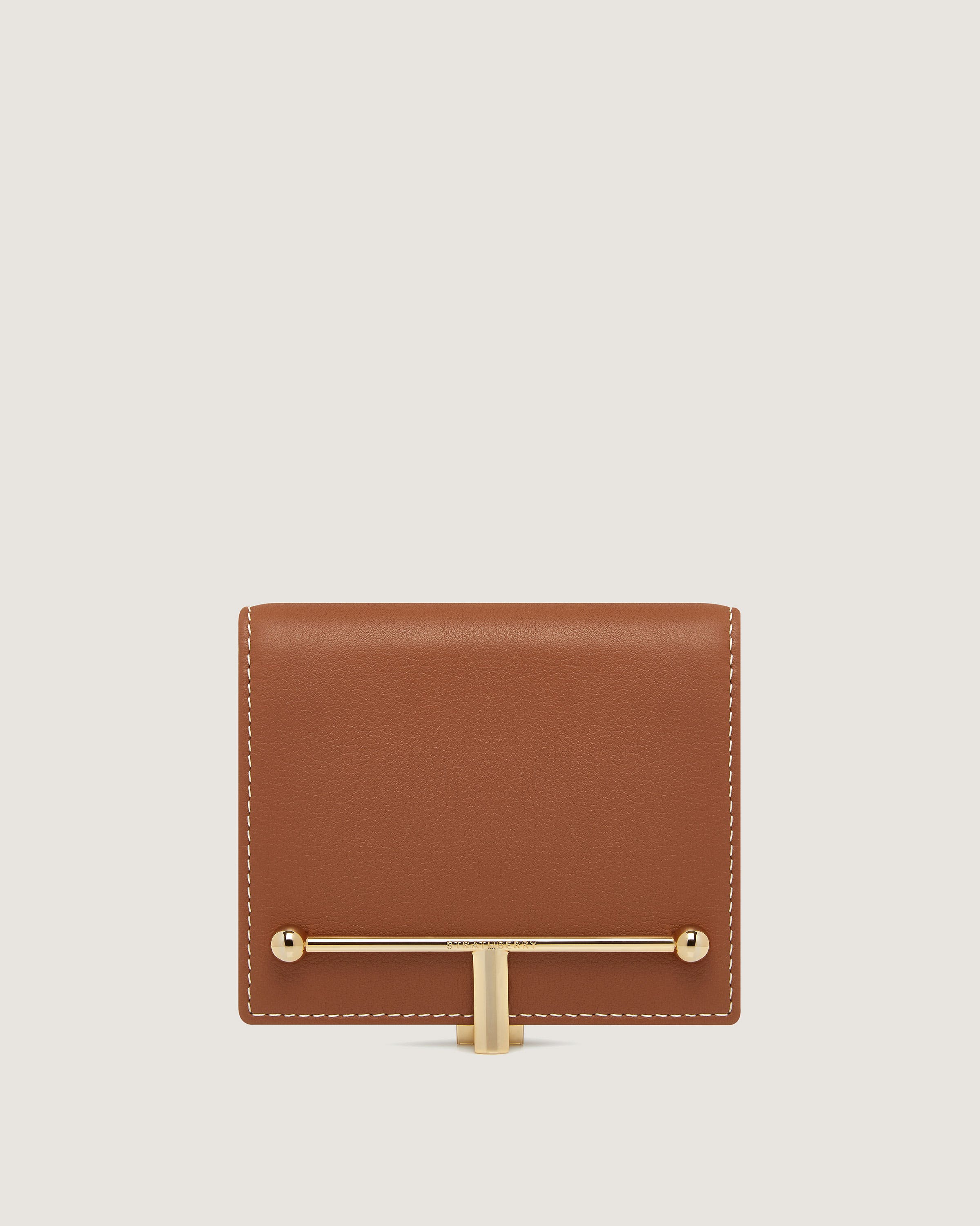 A brown leather wallet with a gold bar on the front