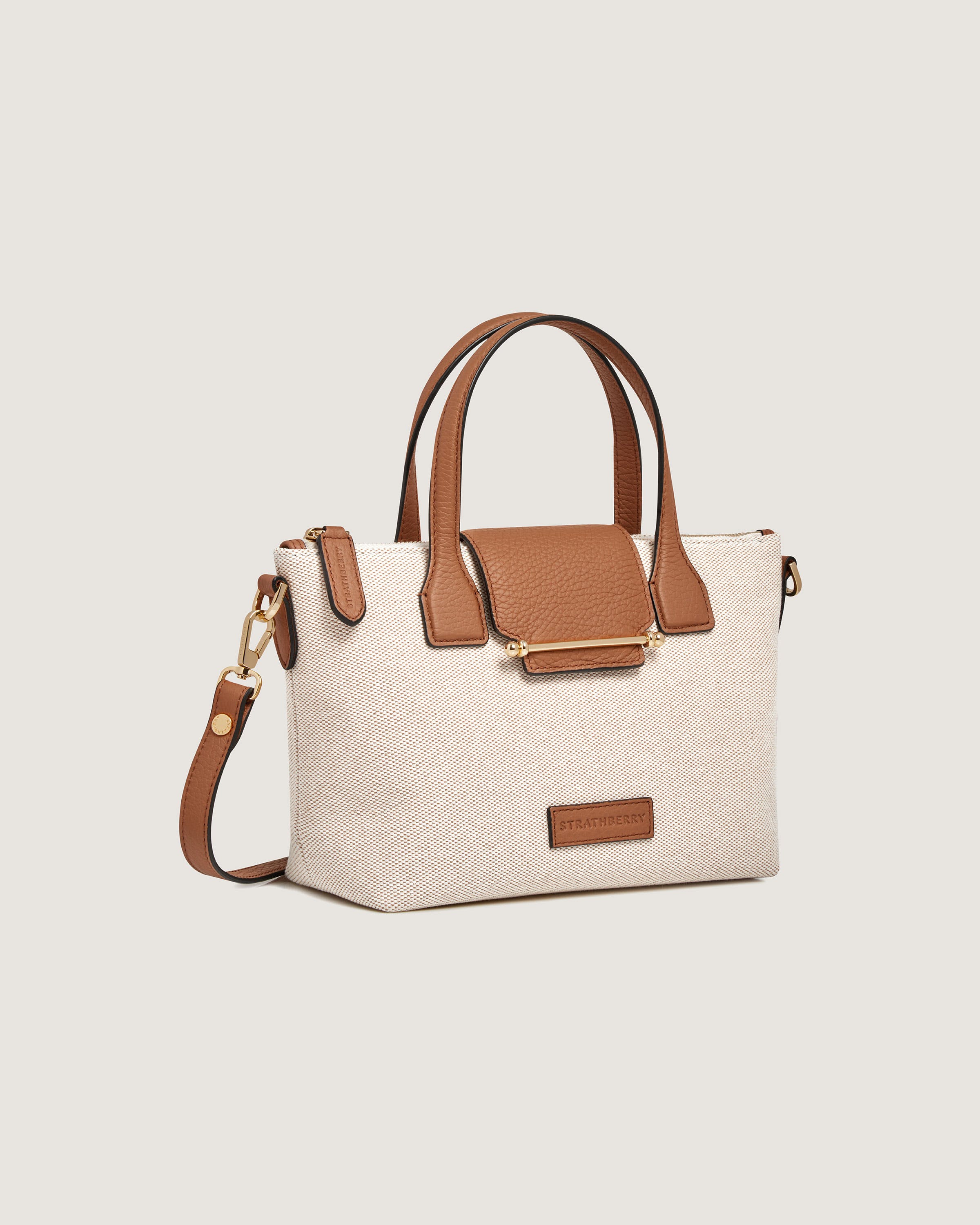 A white and tan purse with a brown handle