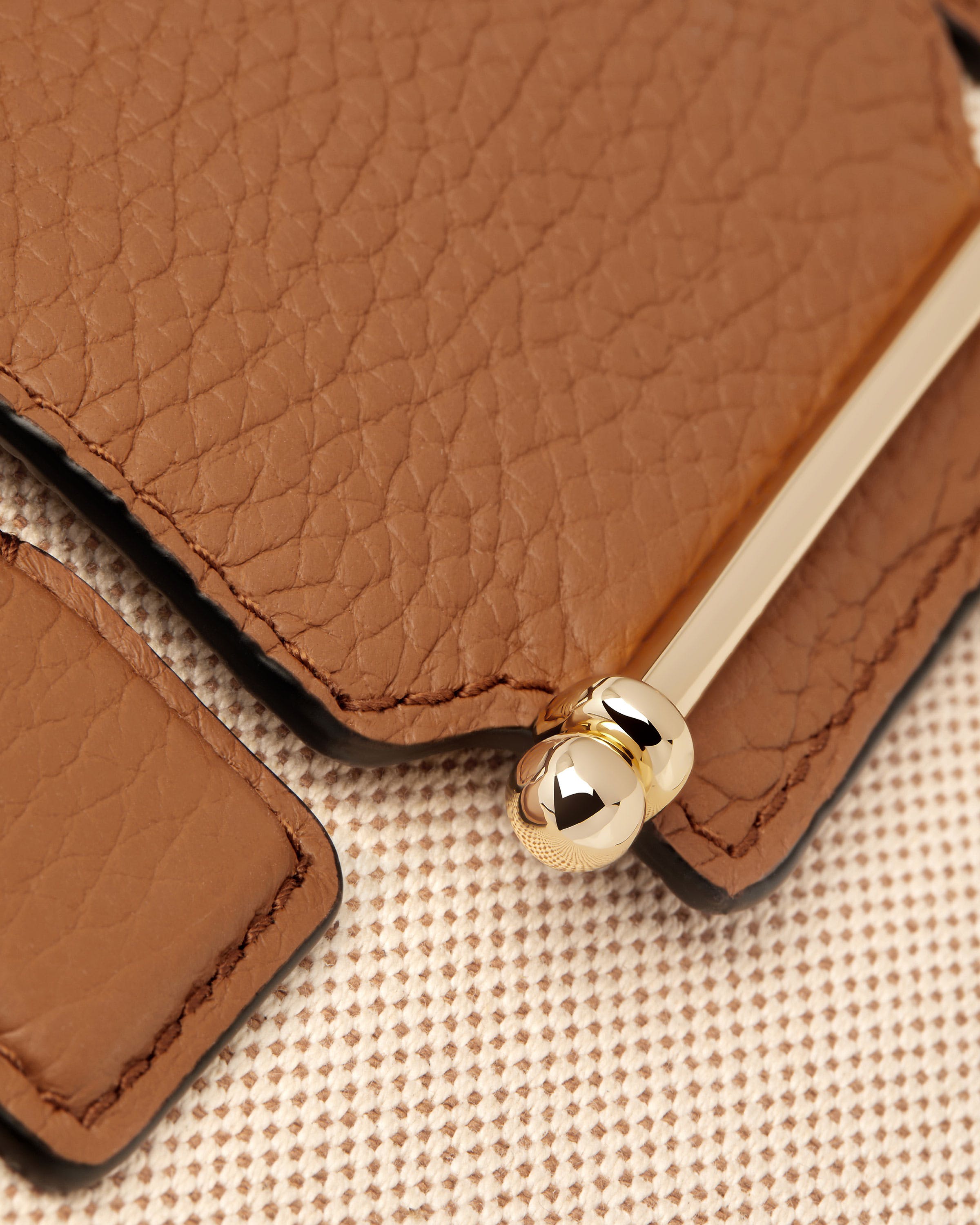 A brown leather purse with a gold ring on it