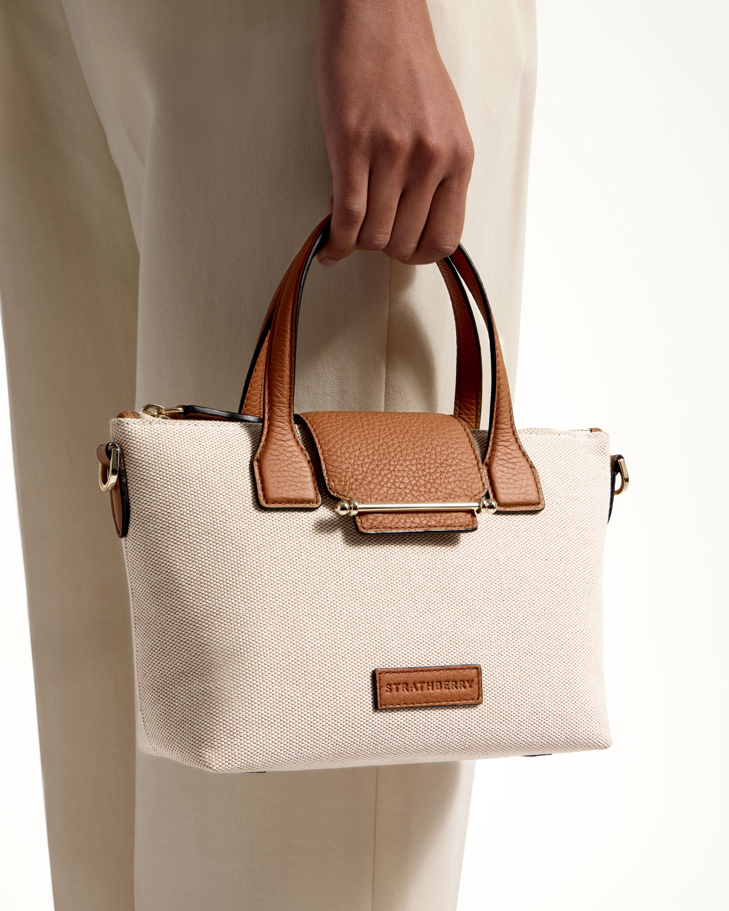 A person holding a white and tan purse