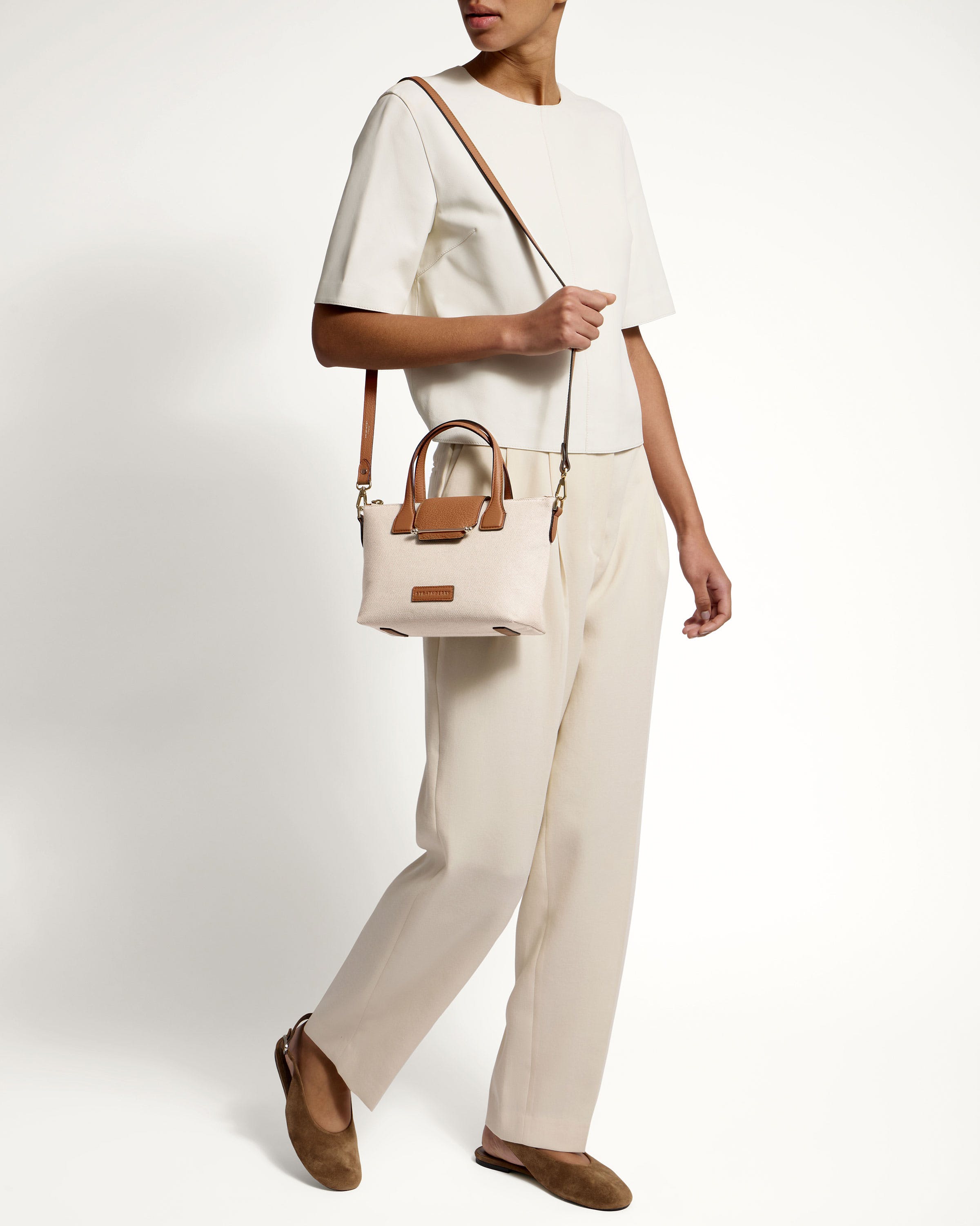 A woman carrying a handbag while standing in front of a white wall