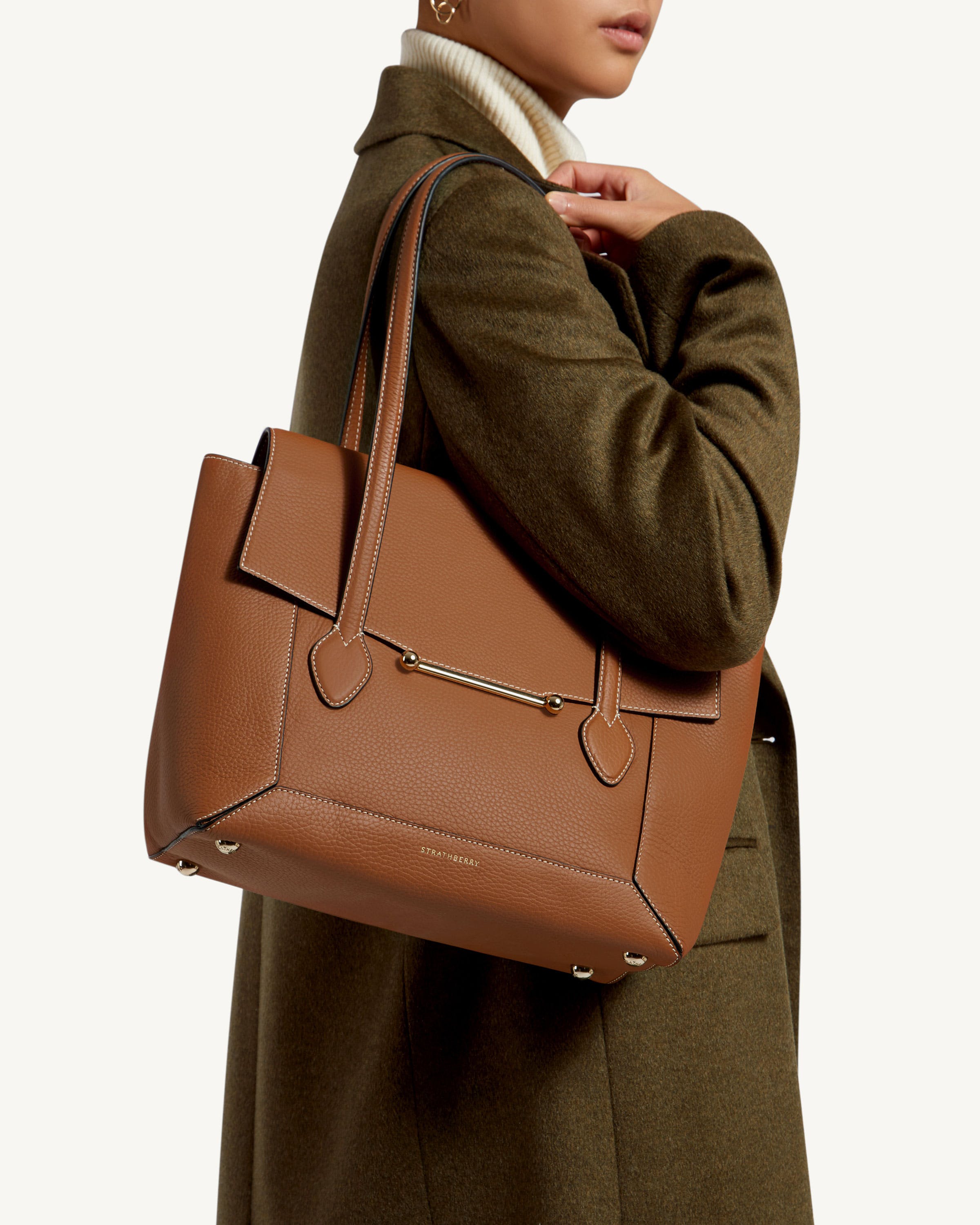 A woman is holding a brown handbag