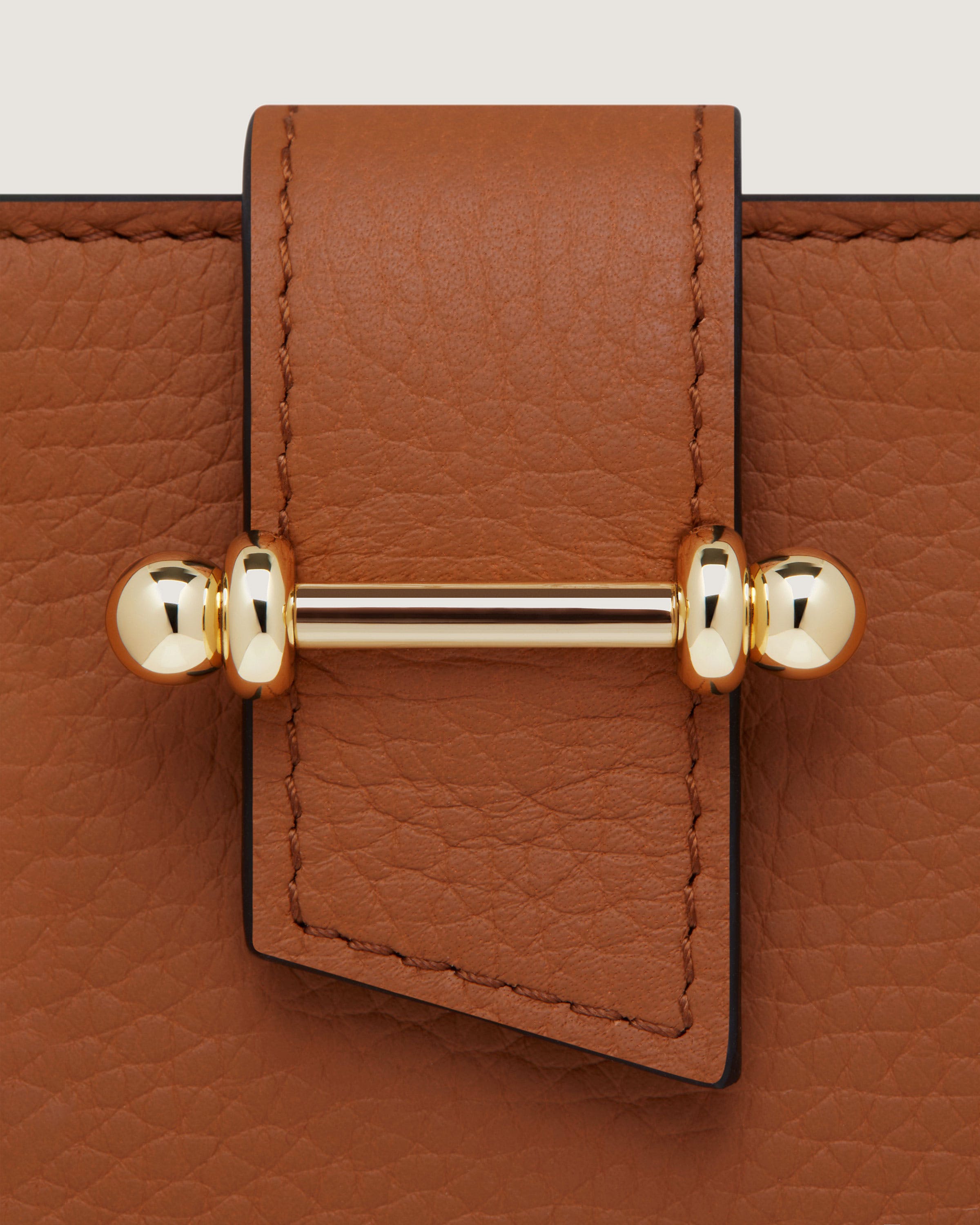 A close up of a brown purse with a gold handle