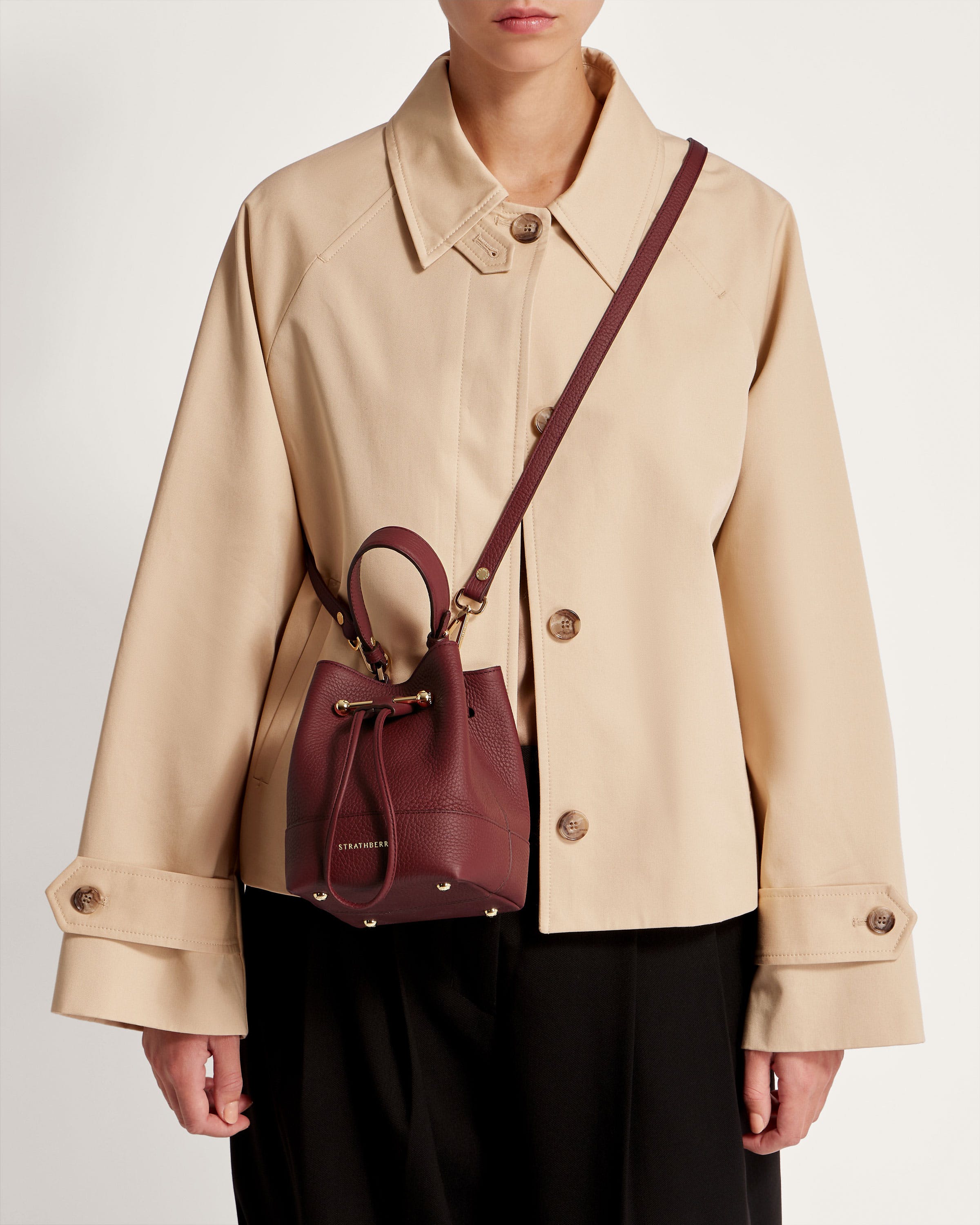 A woman wearing a beige coat and a brown purse