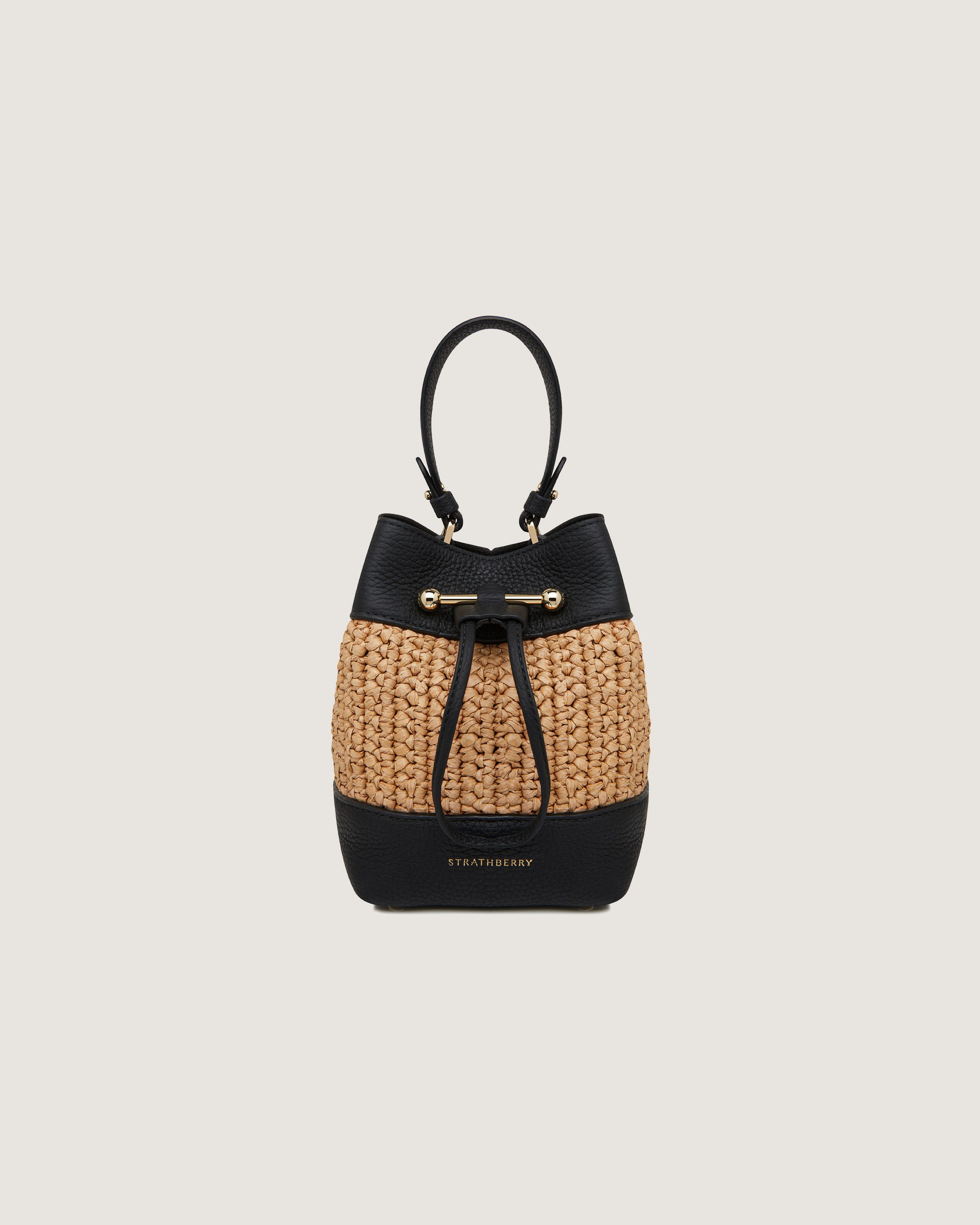 A black and tan straw bag with a black handle