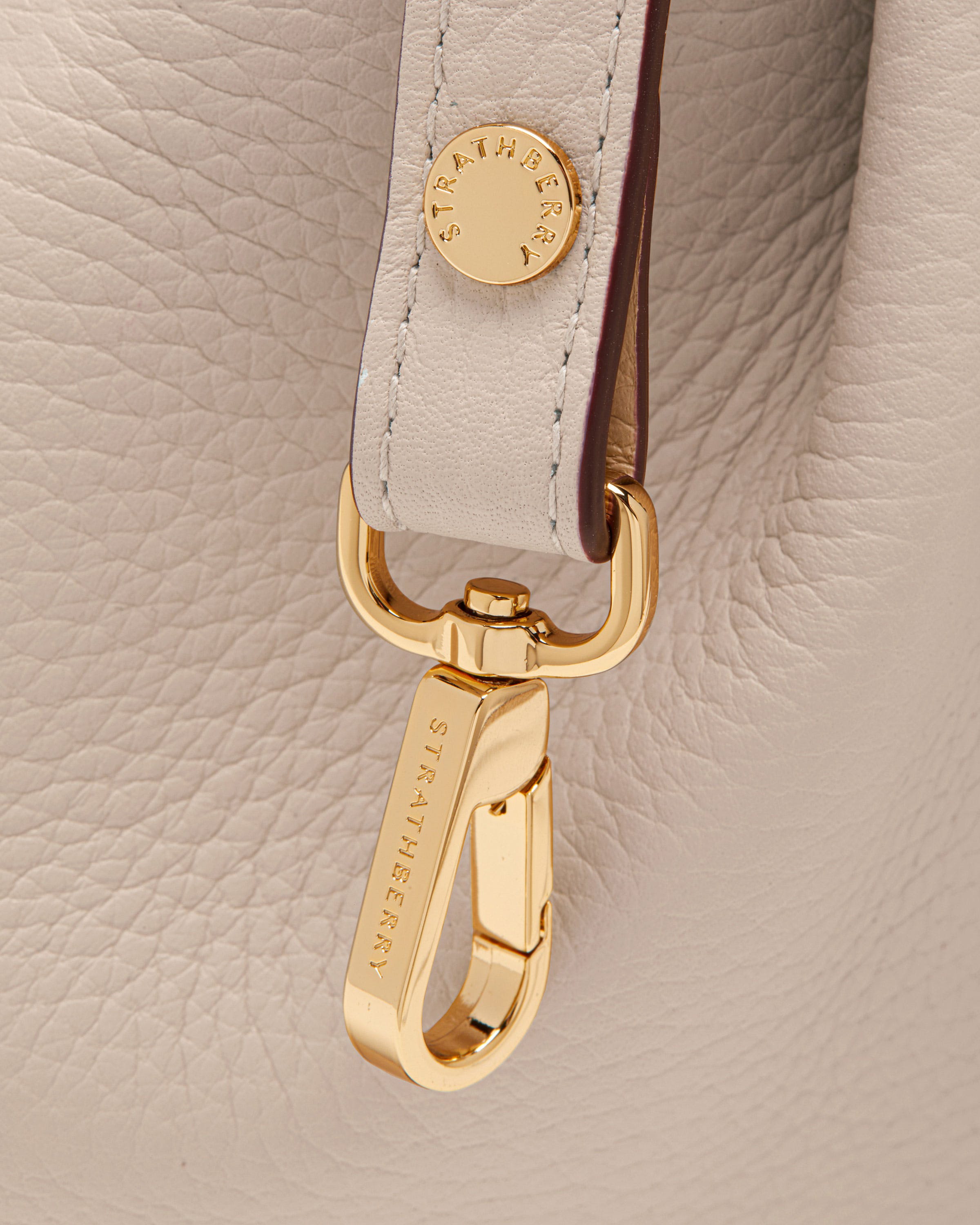 A close up of a white purse with a gold buckle