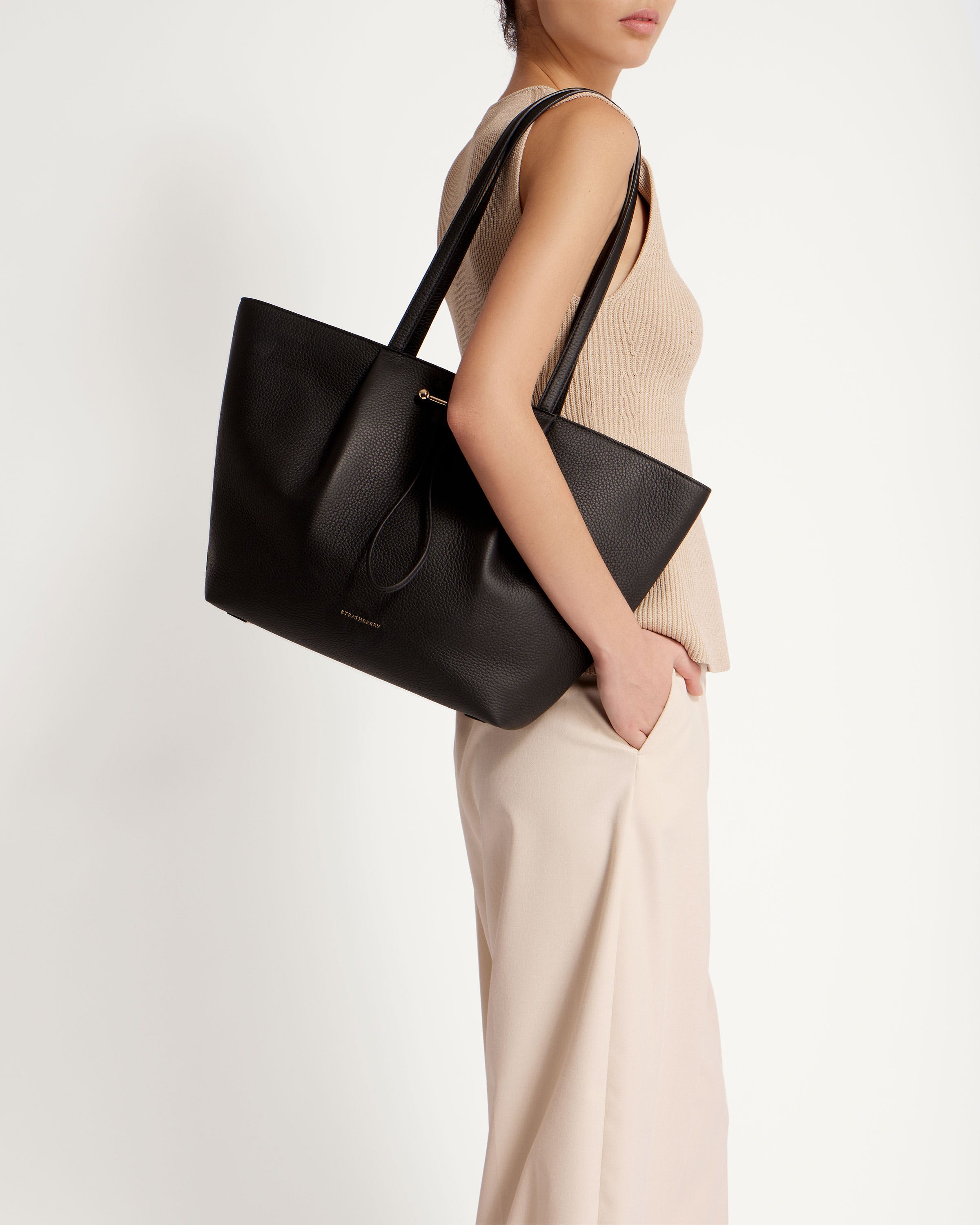 A woman holding a black handbag on a white background