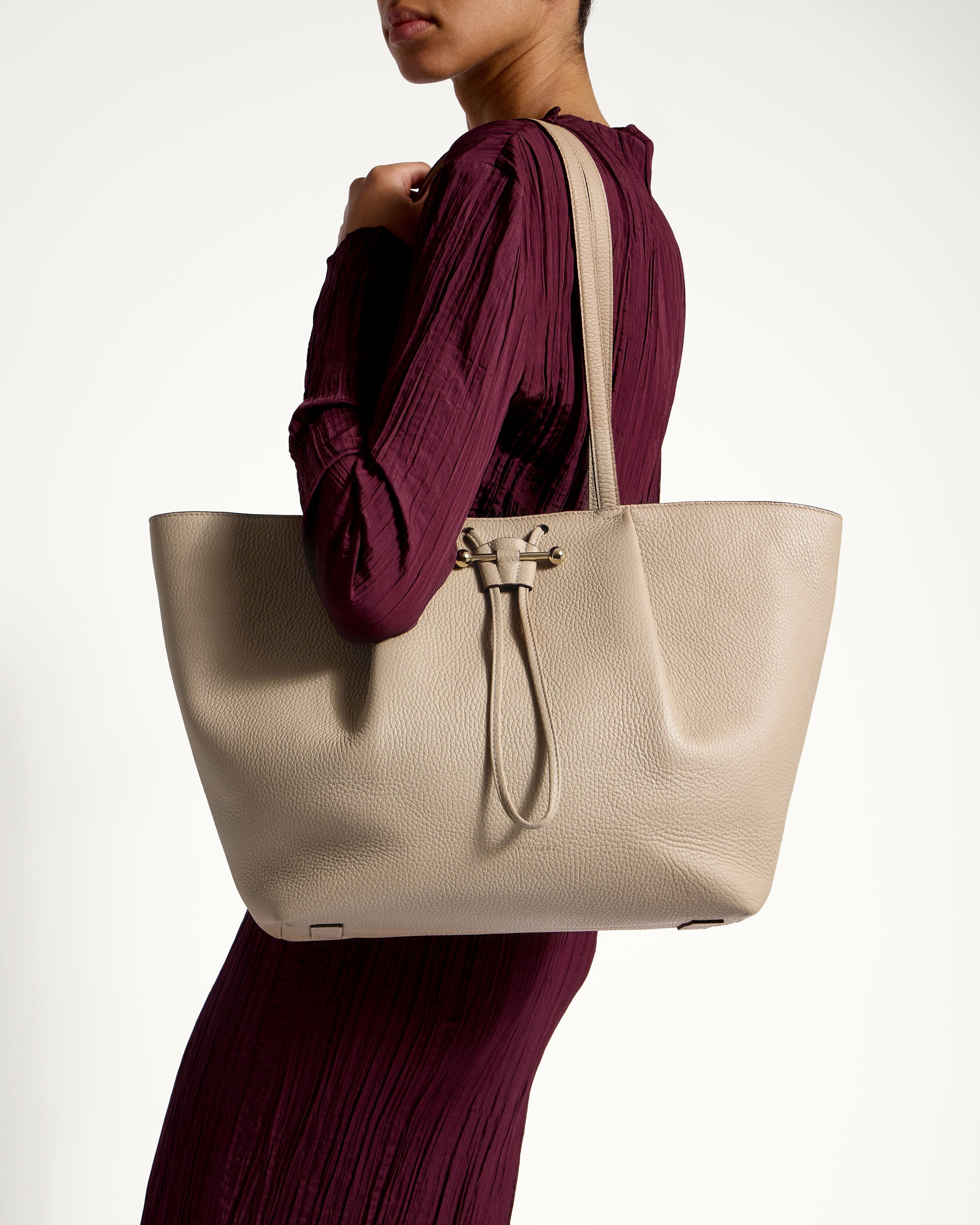 A woman in a maroon dress holding a white bag