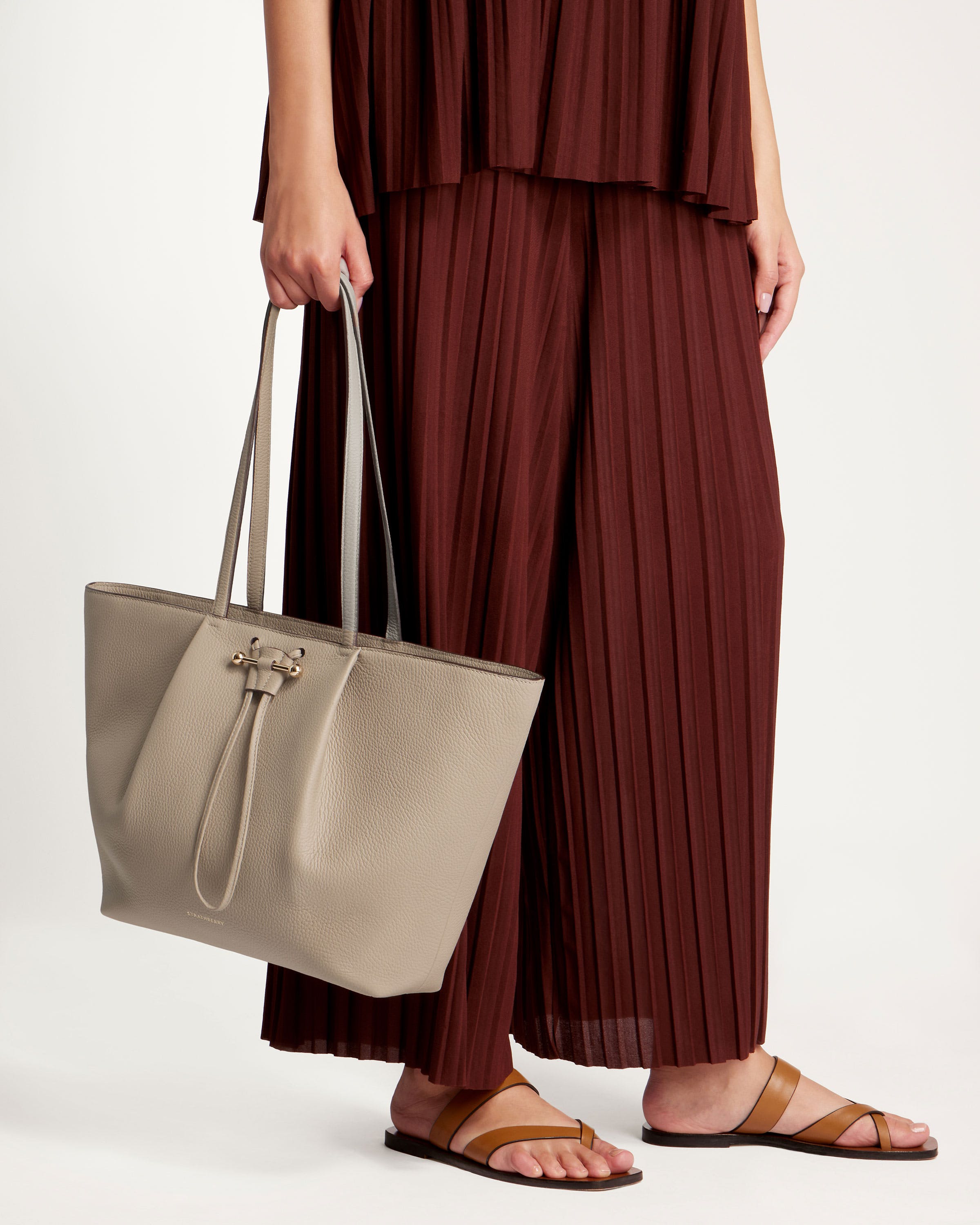 A woman is holding a beige purse