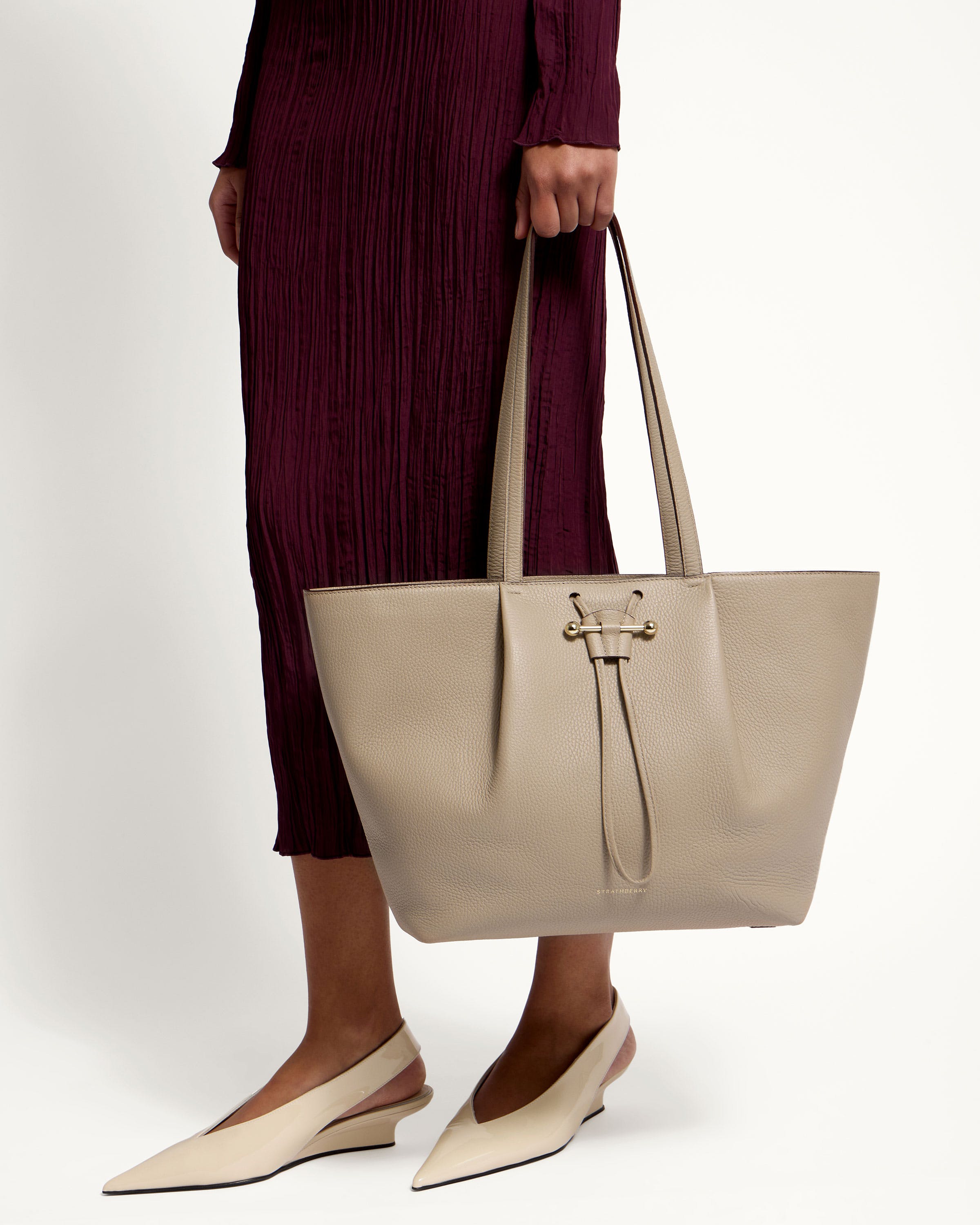 A woman is holding a beige purse