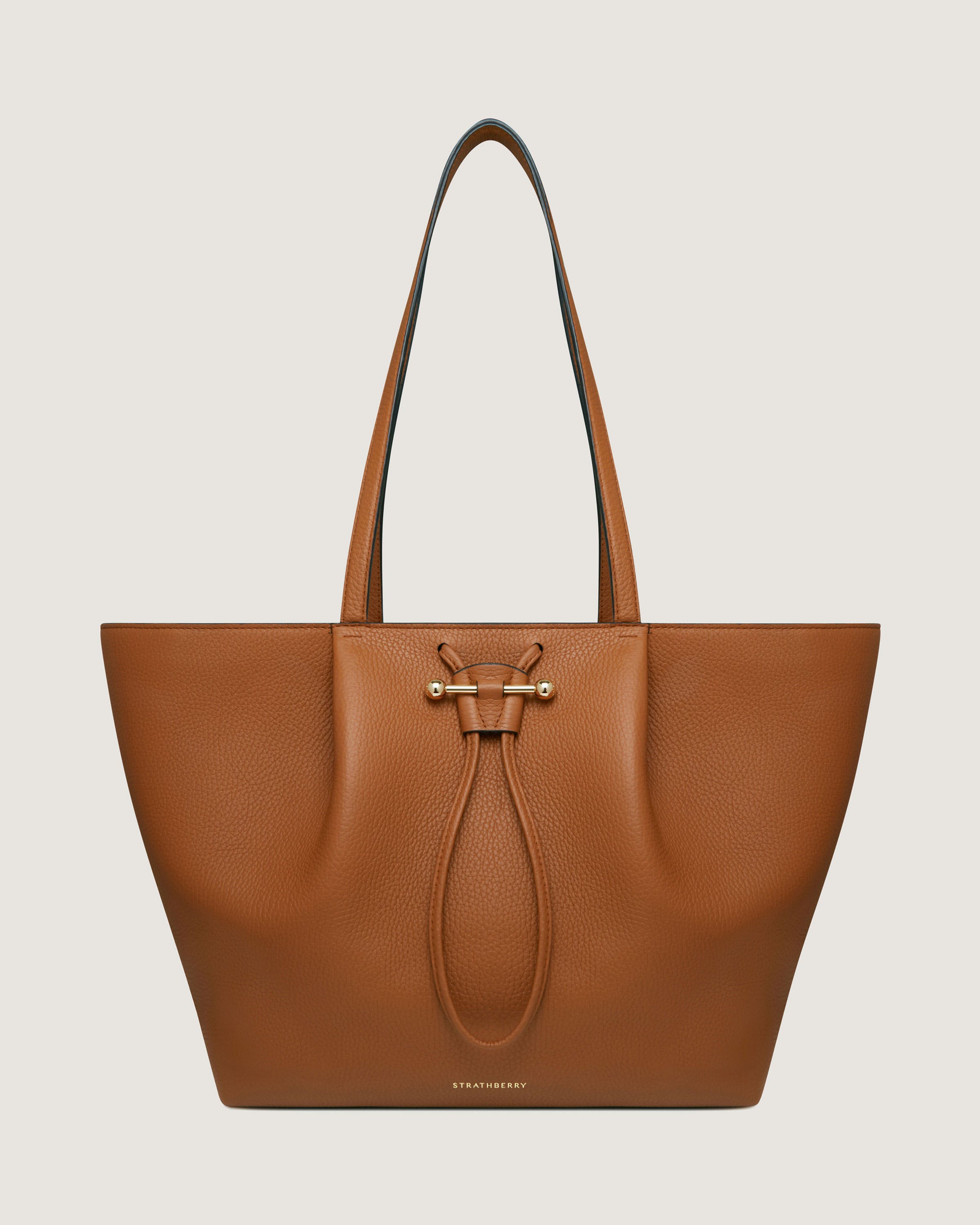 A tan leather tote bag on a white background