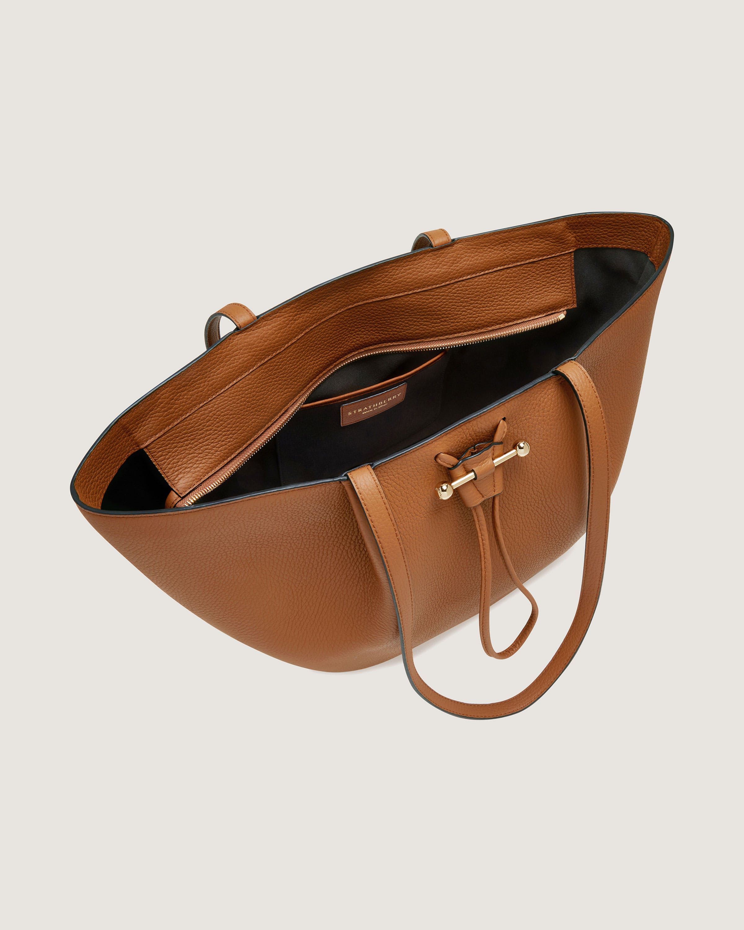 A tan leather handbag with a long strap