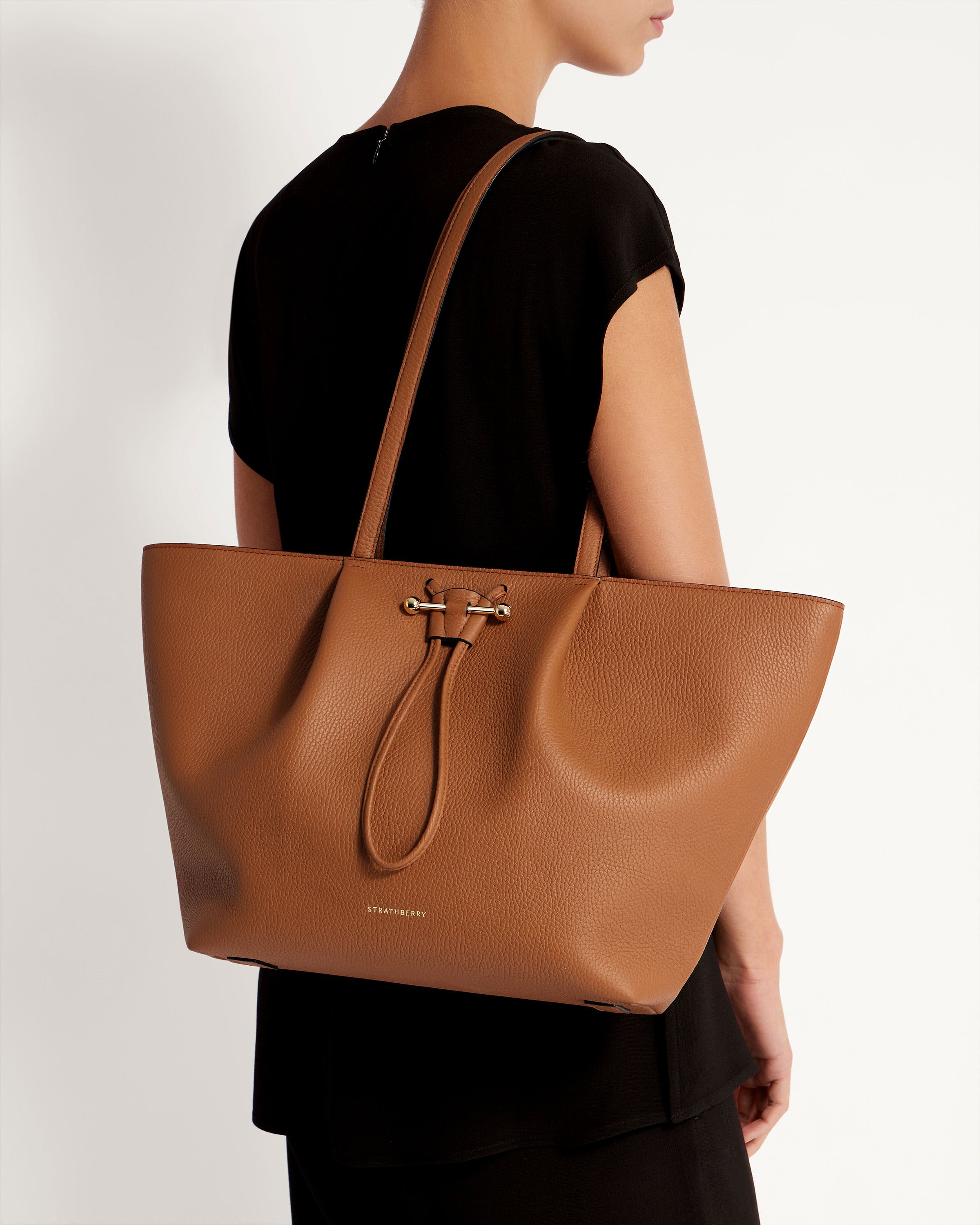 A woman carrying a tan leather tote bag