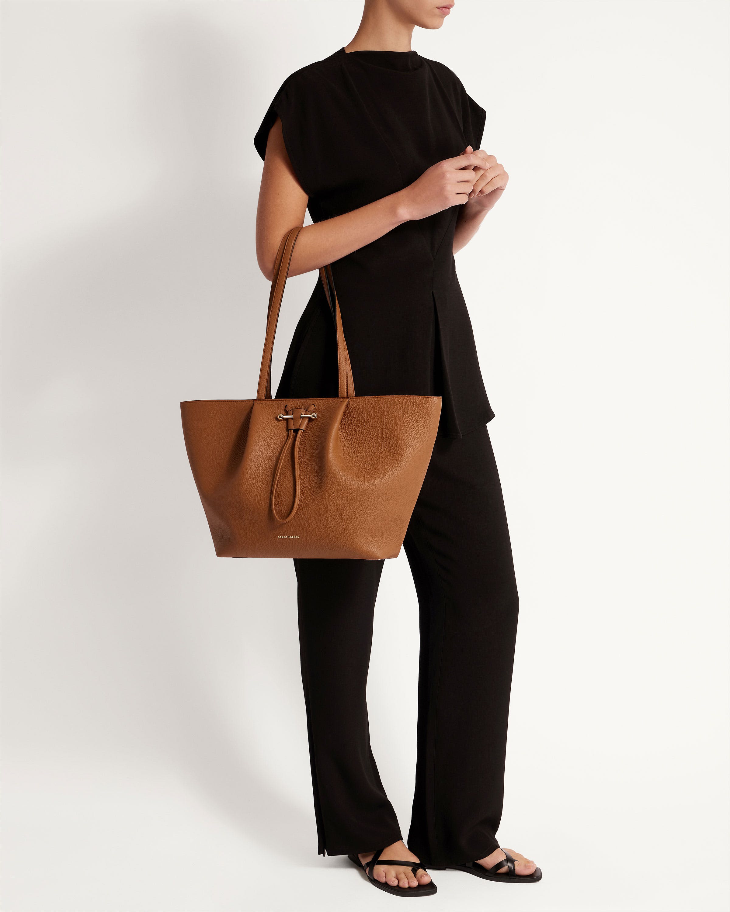 A woman is holding a brown handbag