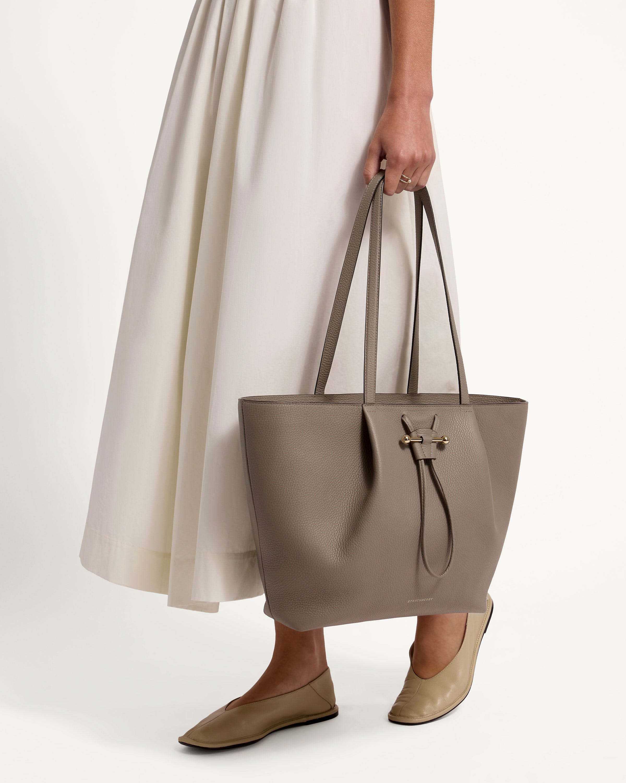 A woman in a white dress holding a gray bag