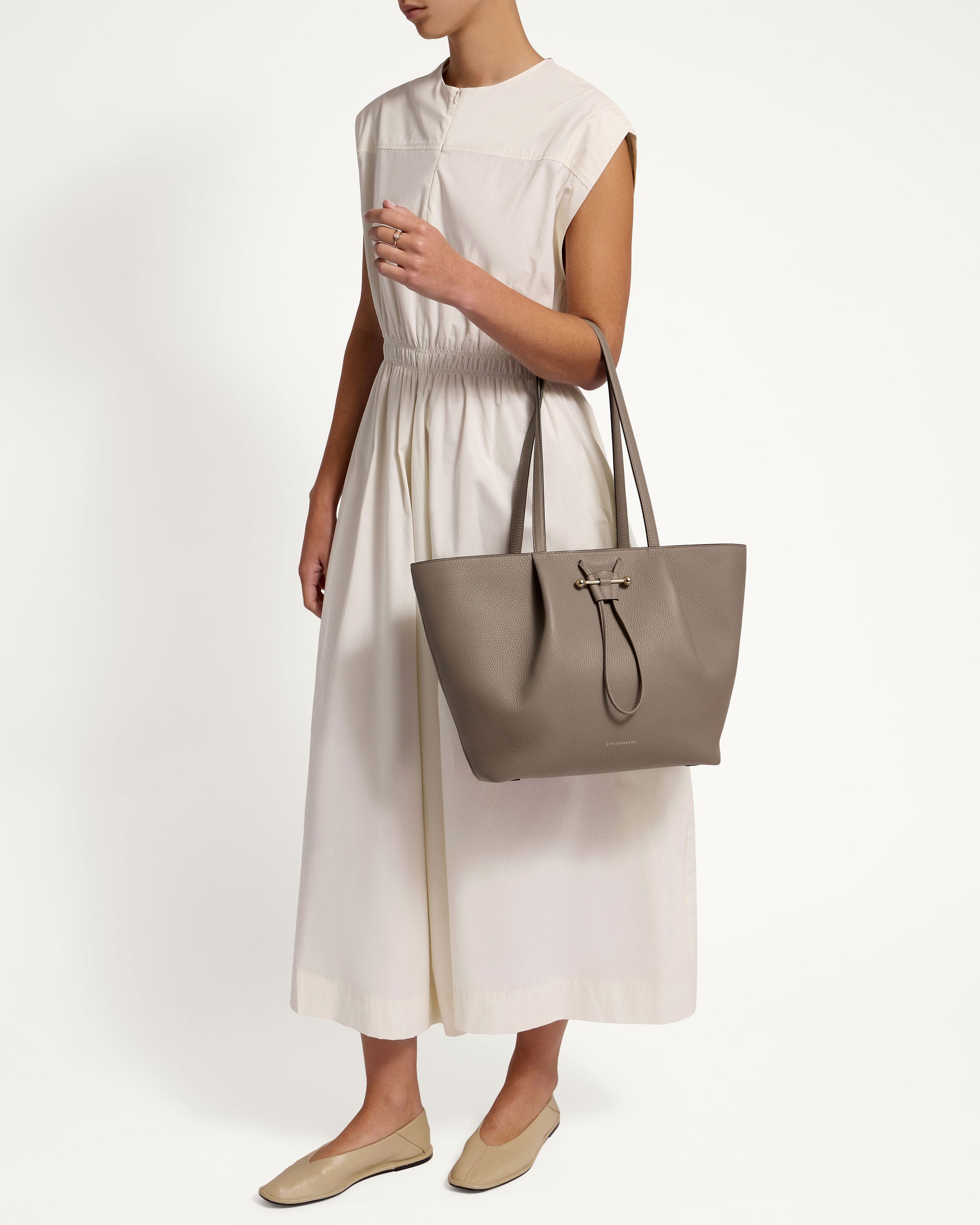 A woman in a white dress holding a gray bag