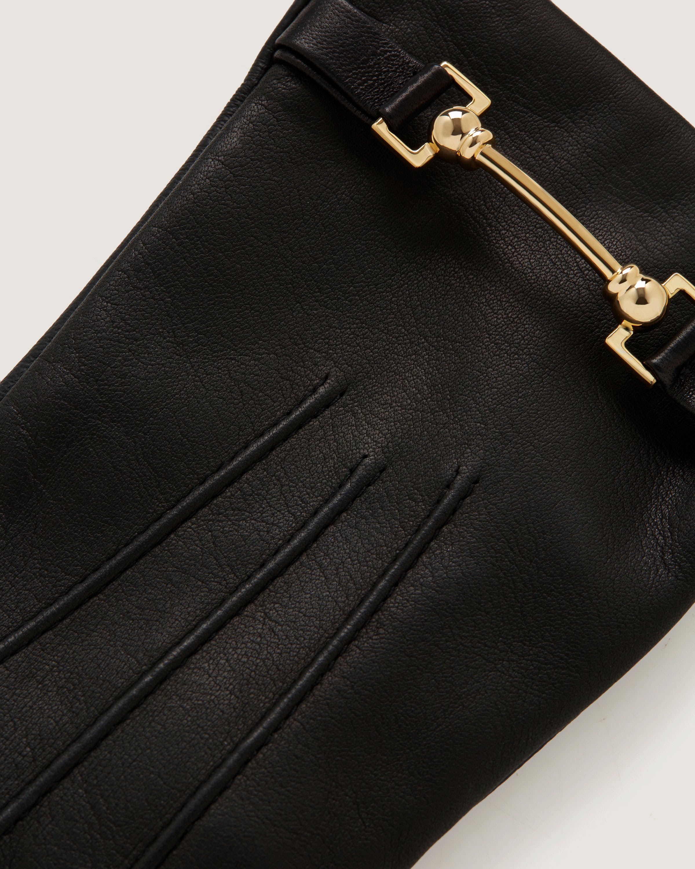 A close up of a black purse on a white surface