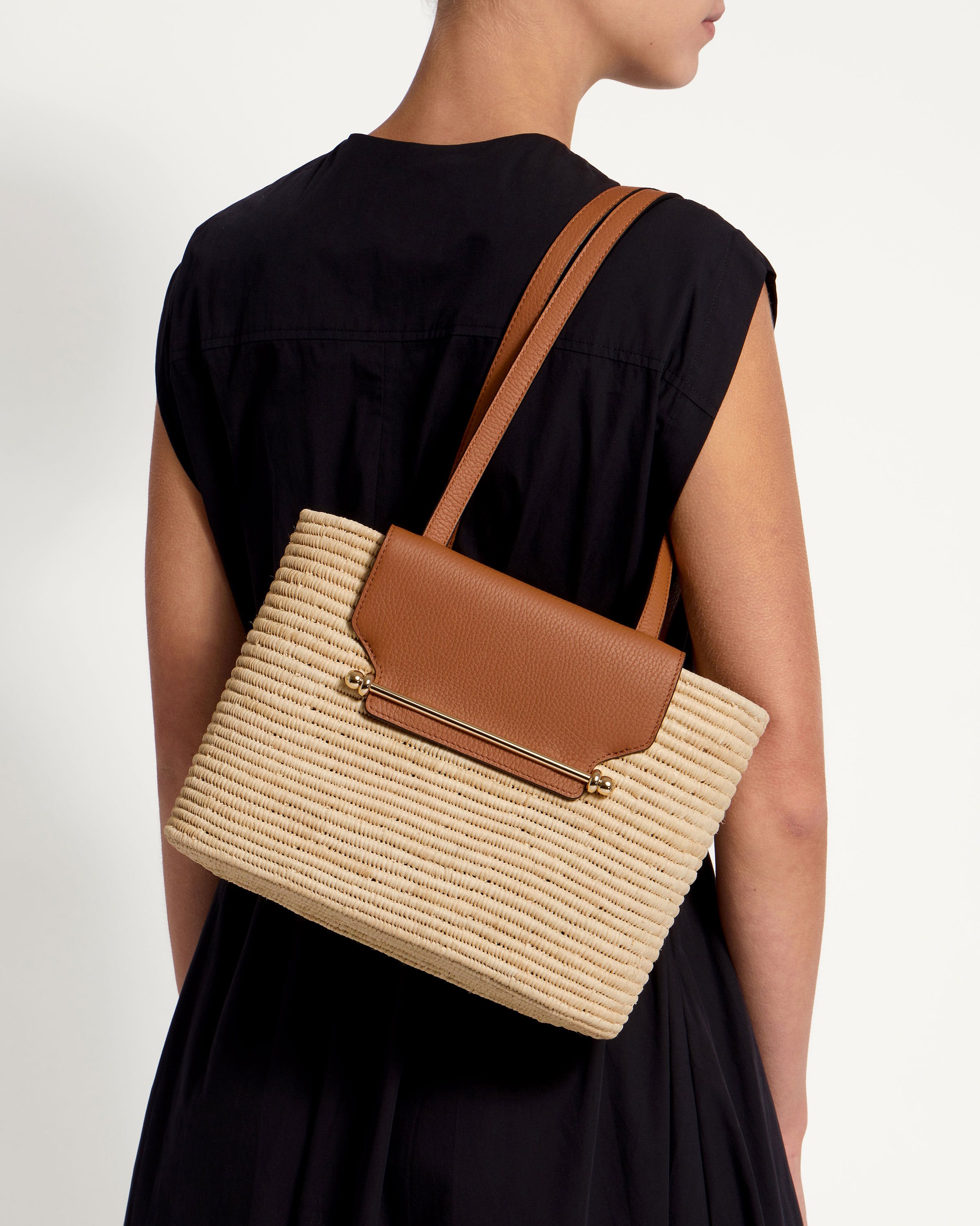 A woman wearing a black dress carrying a brown and tan handbag