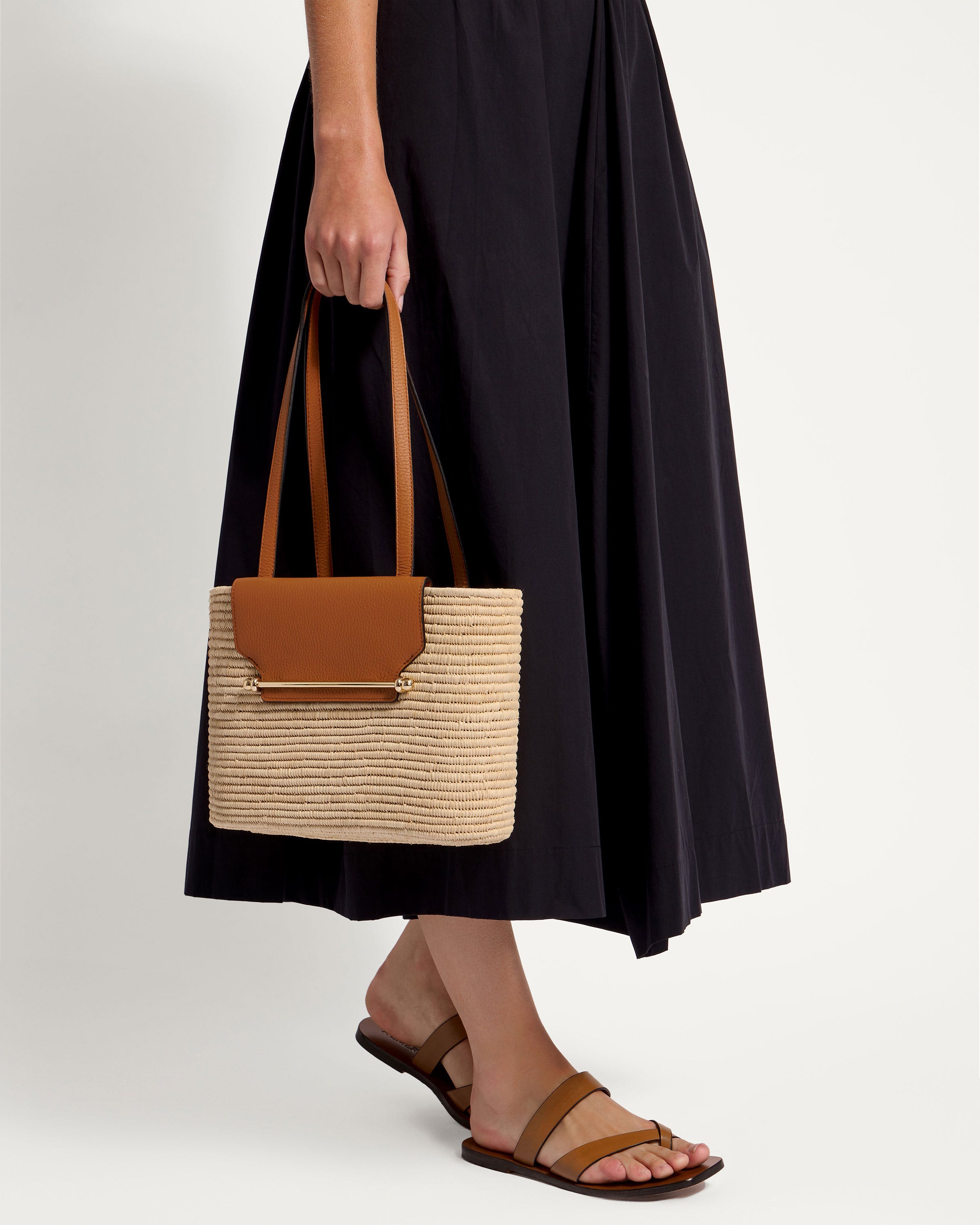 A woman in a black dress holding a brown and white bag