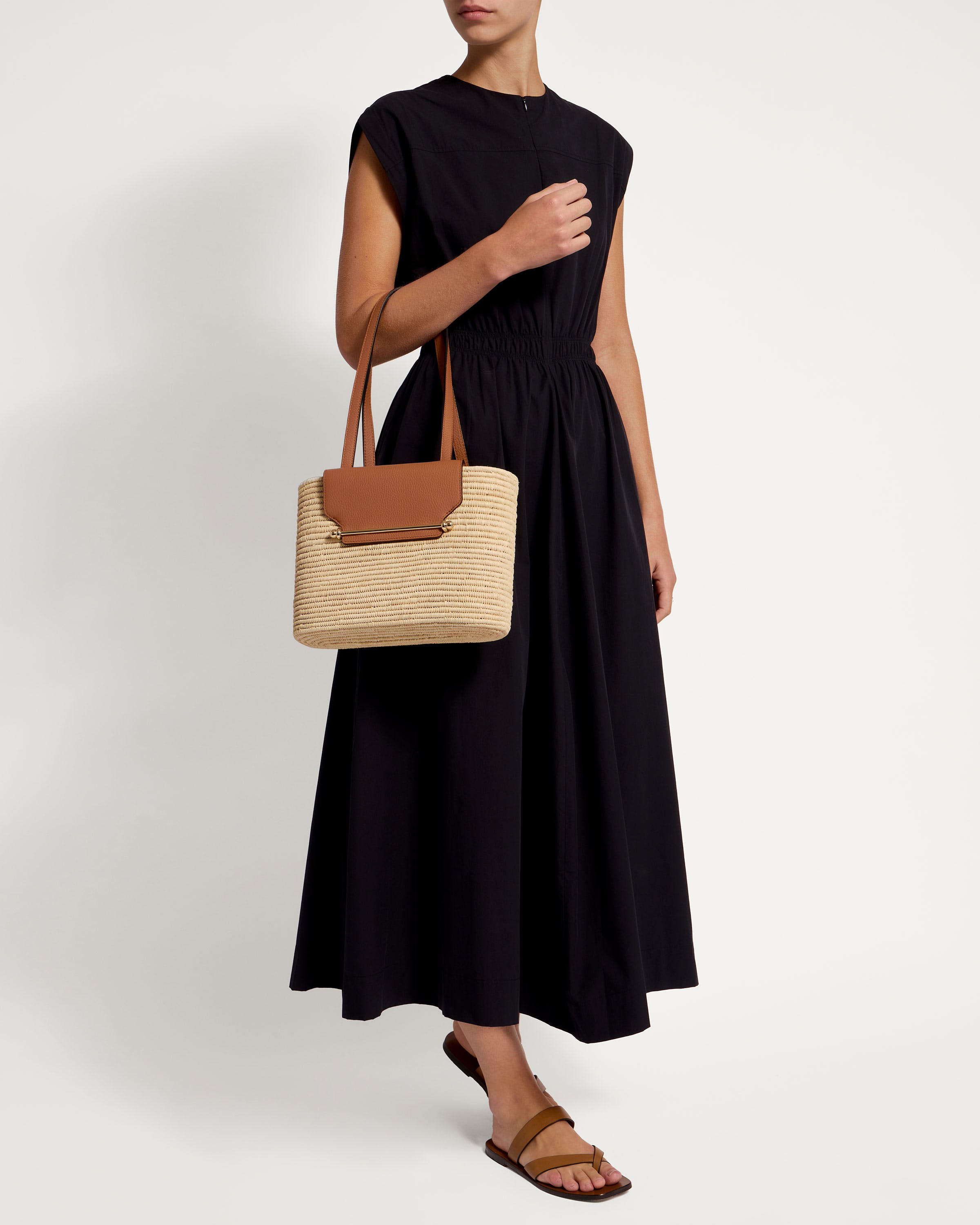 A woman in a black dress holding a brown bag