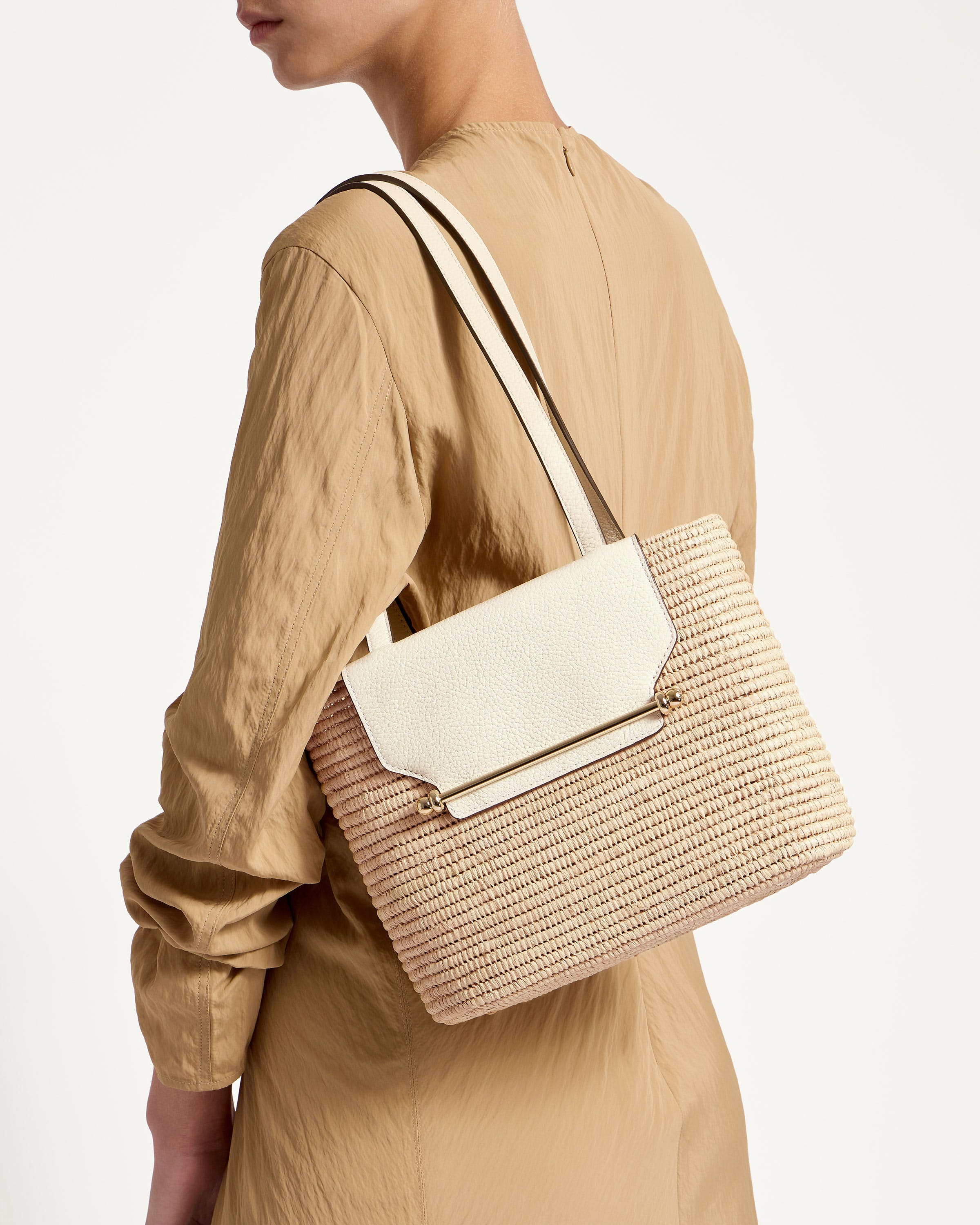 A woman carrying a beige and white handbag