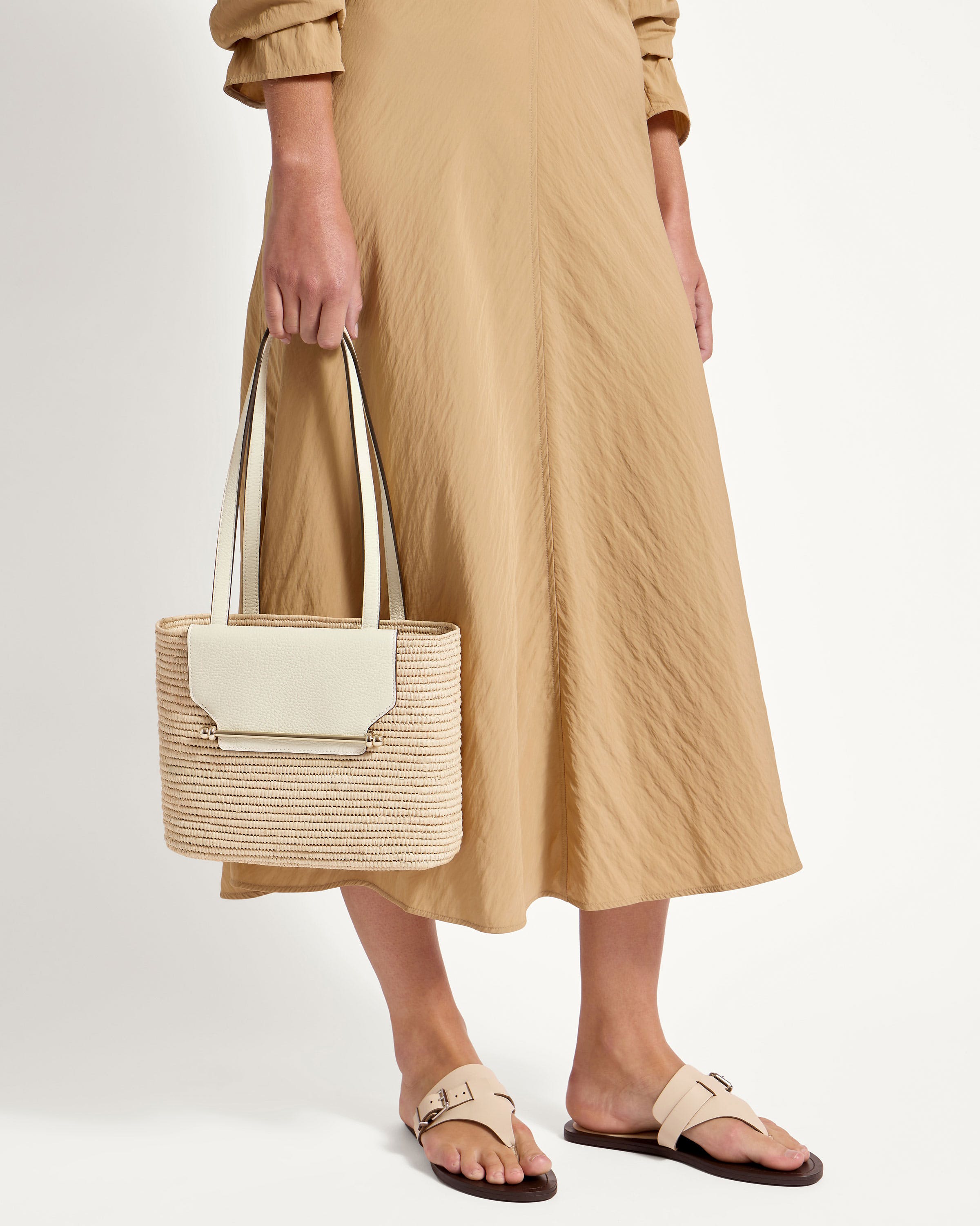 A woman in a tan dress holding a white bag