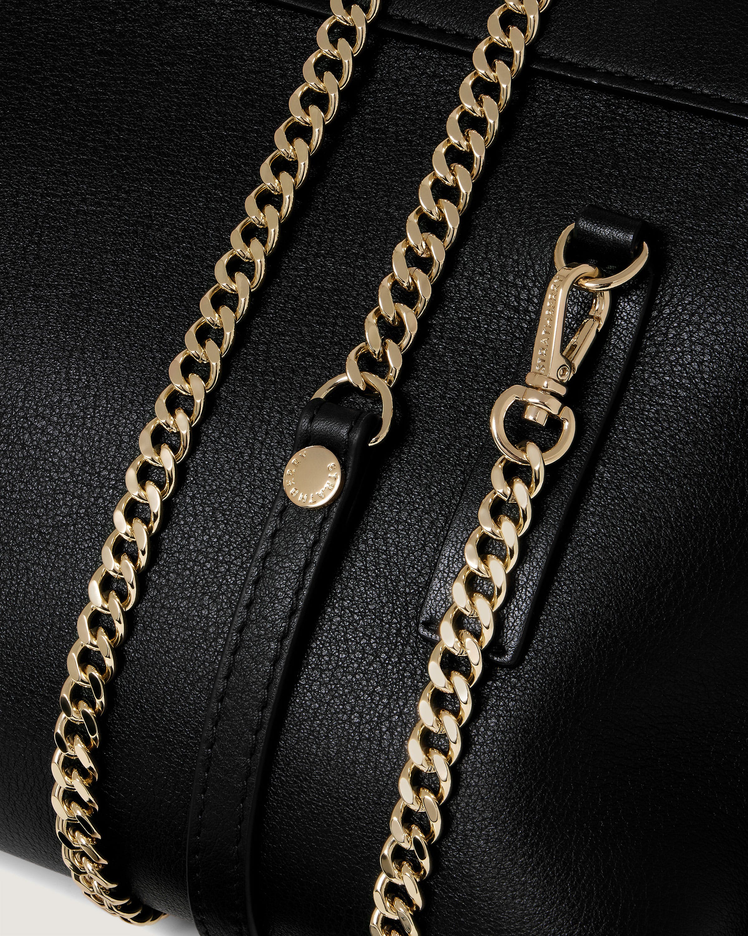 A close up of a black purse with a gold chain