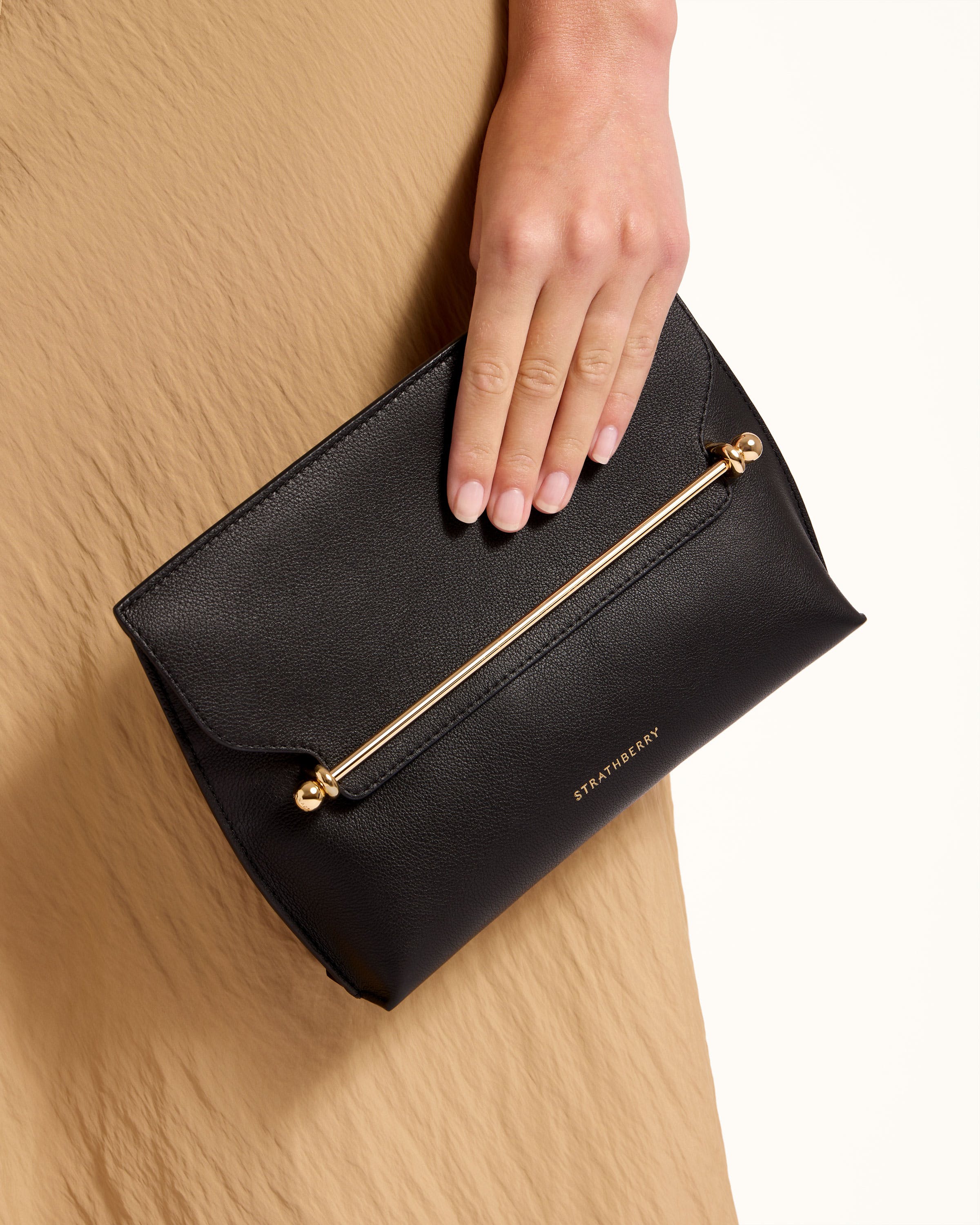 A woman's hand is holding a black purse