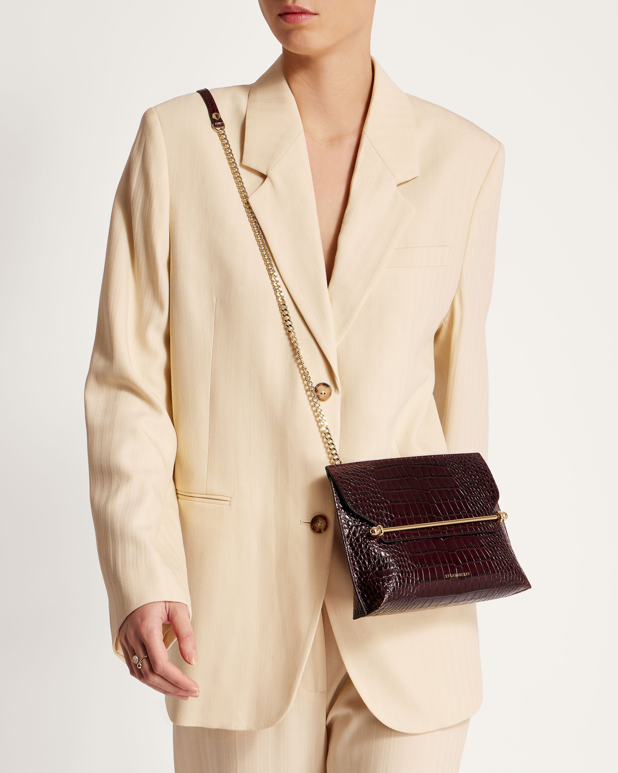 A woman in a white suit holding a brown purse