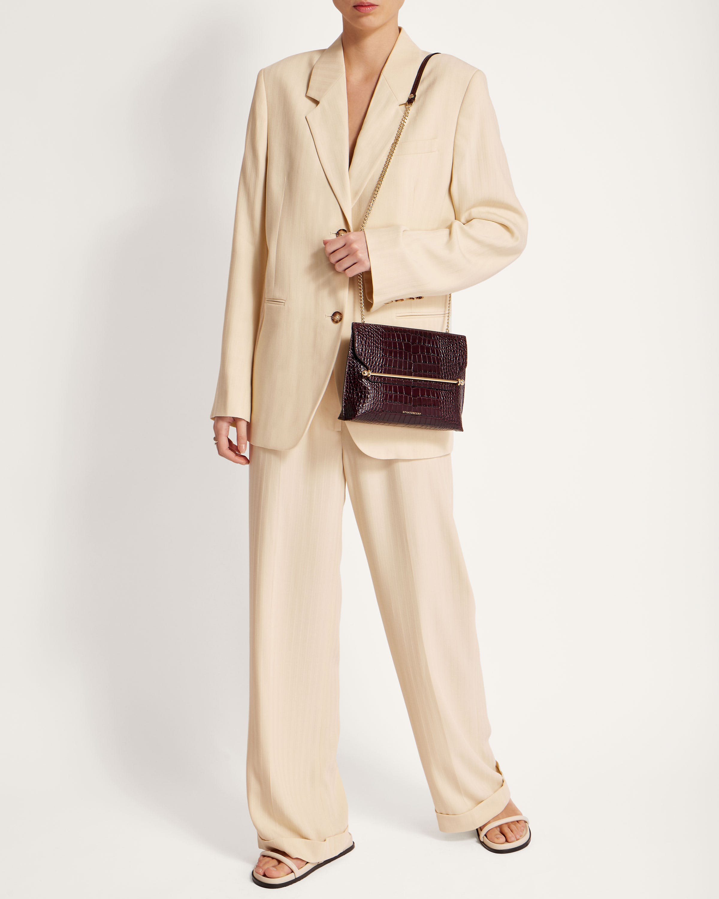 A woman in a beige suit holding a black purse