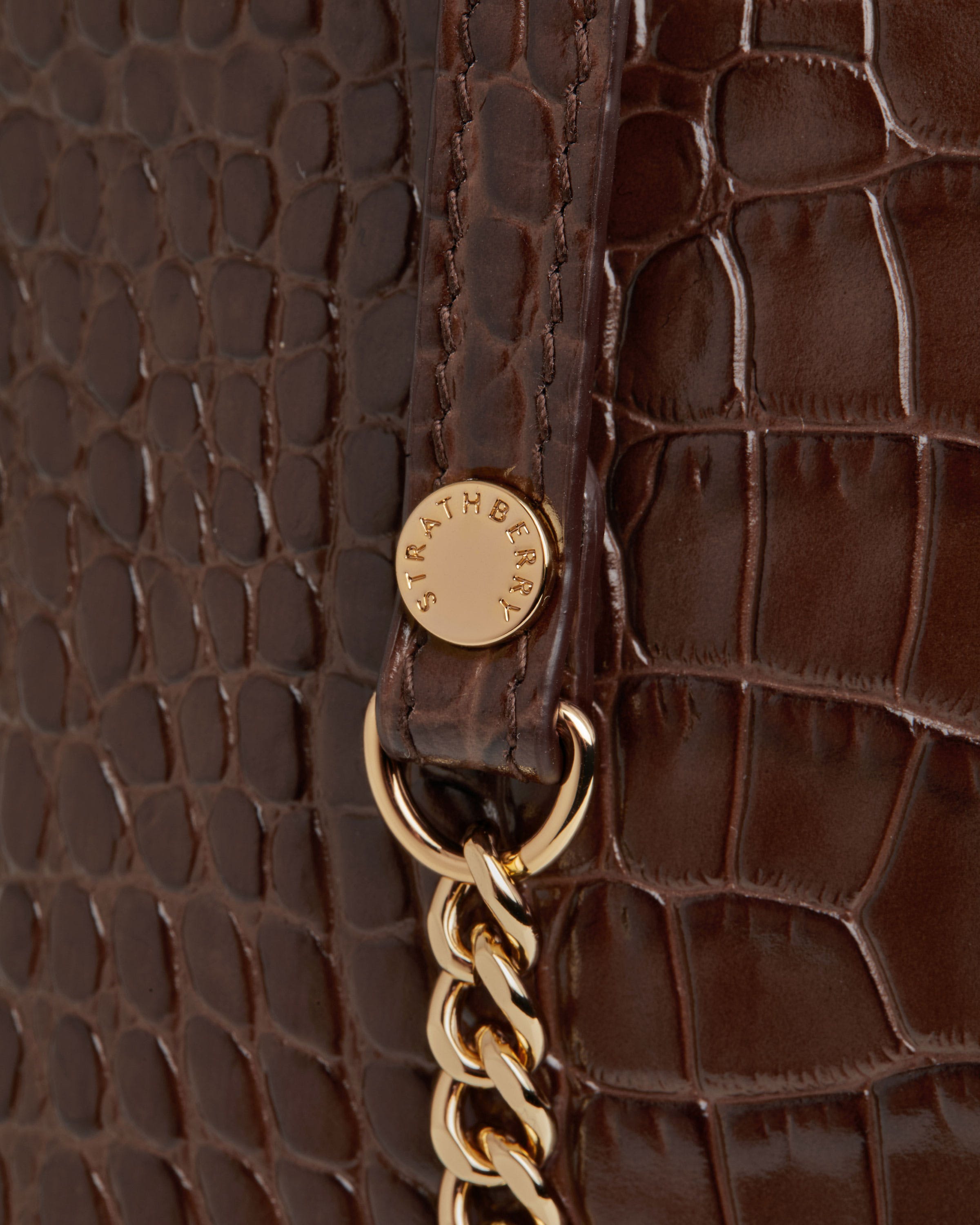 A close up of a brown purse with a gold chain