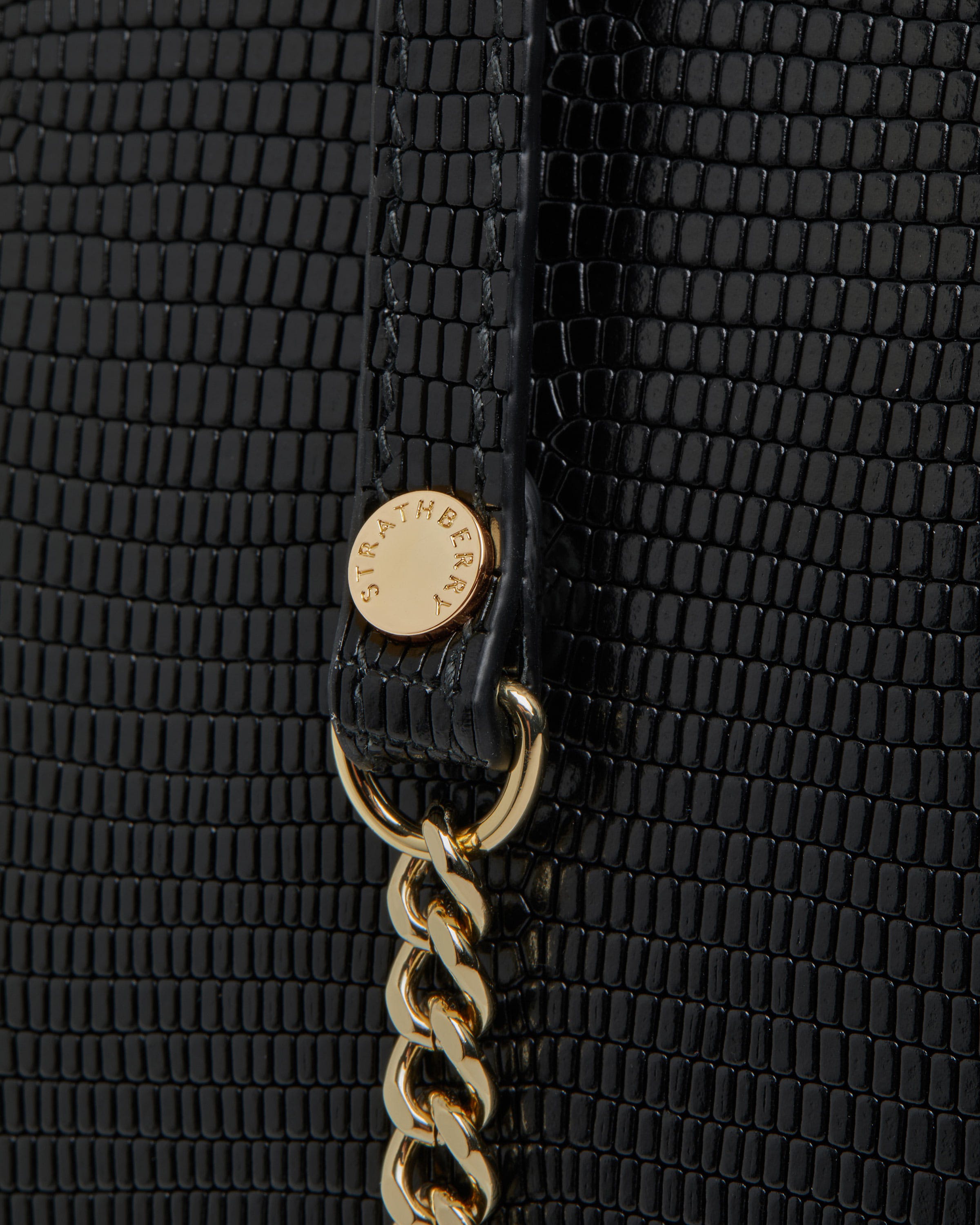 A close up of a black purse with a gold chain