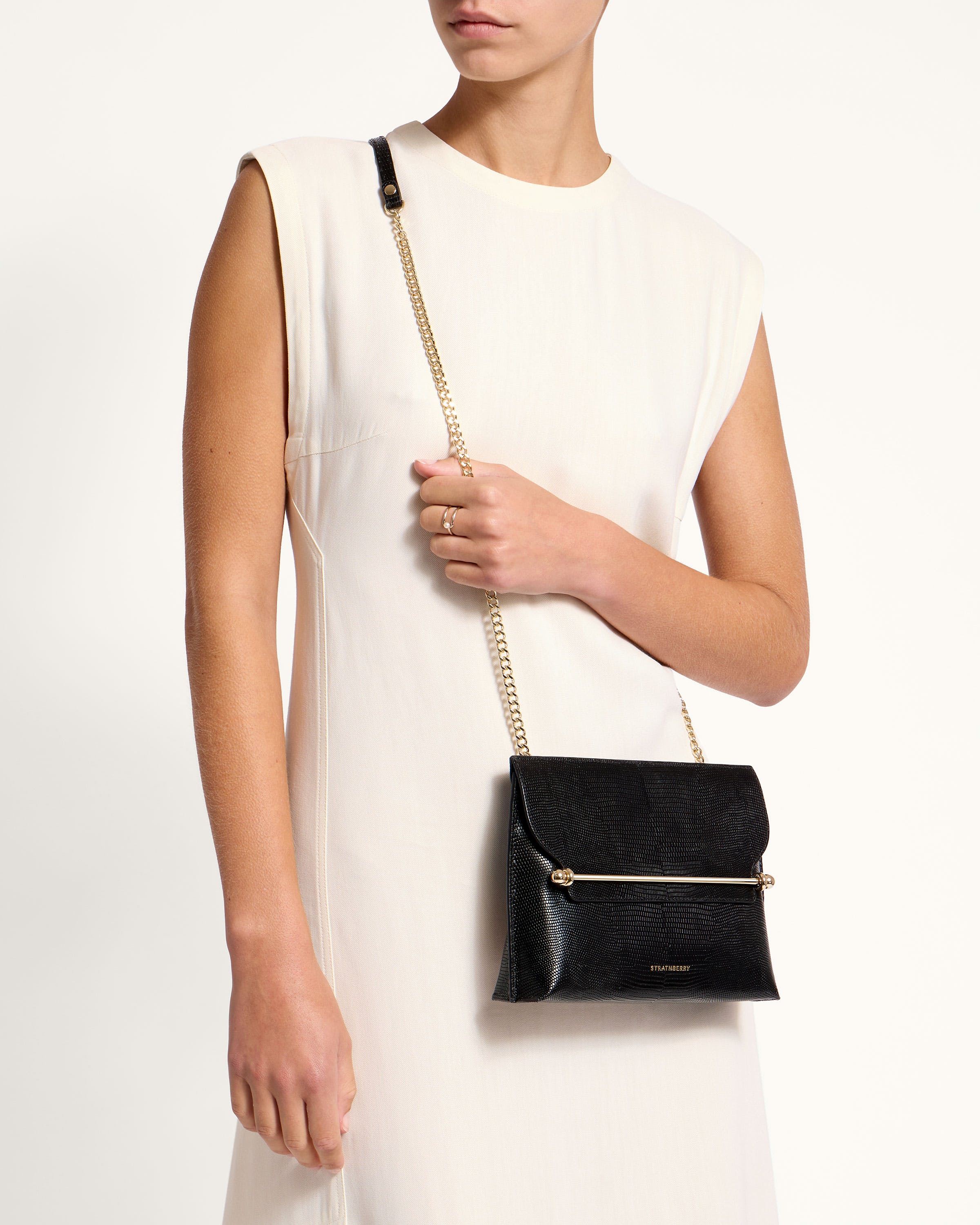 A woman in a white dress holding a black purse