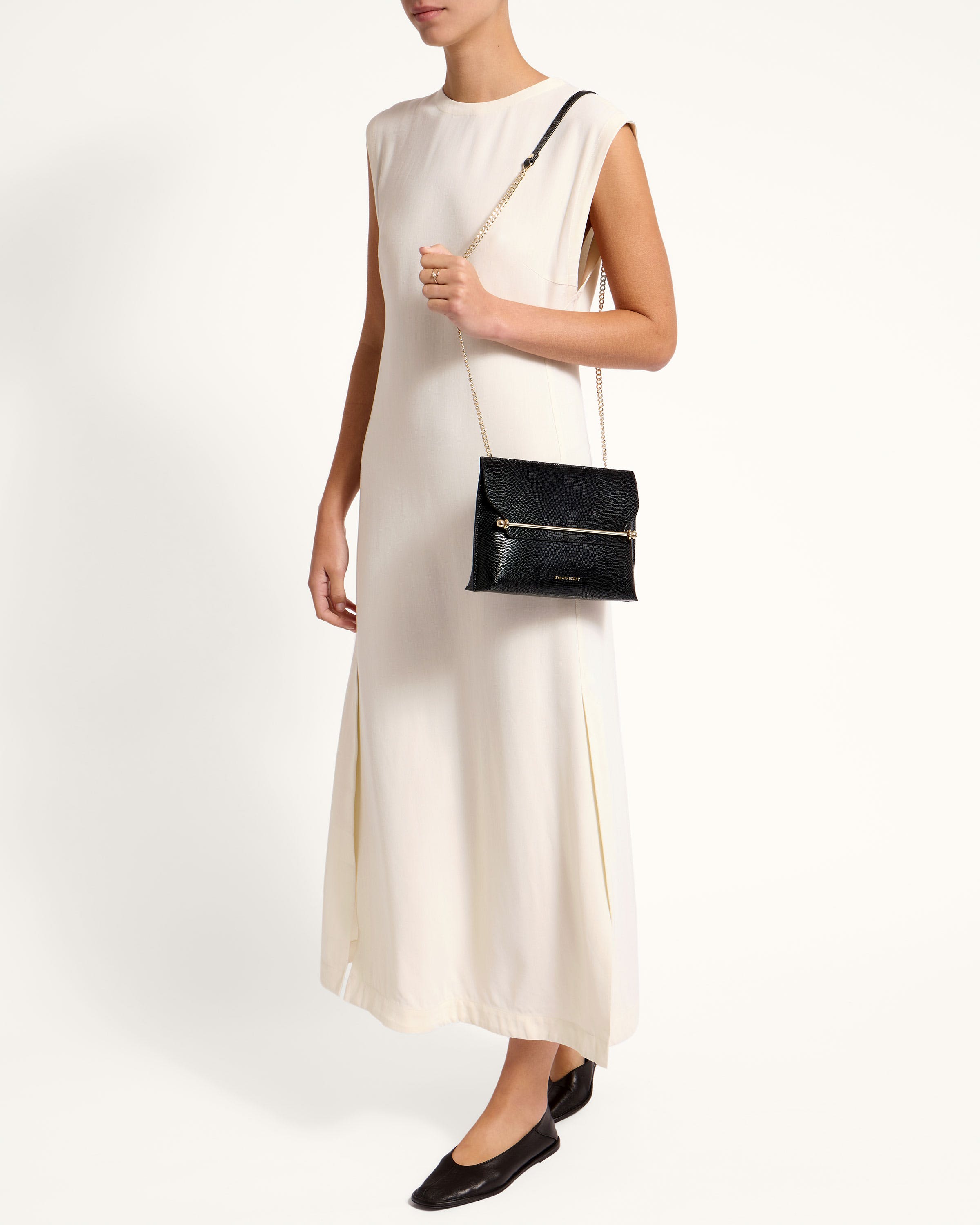 A woman in a white dress holding a black purse