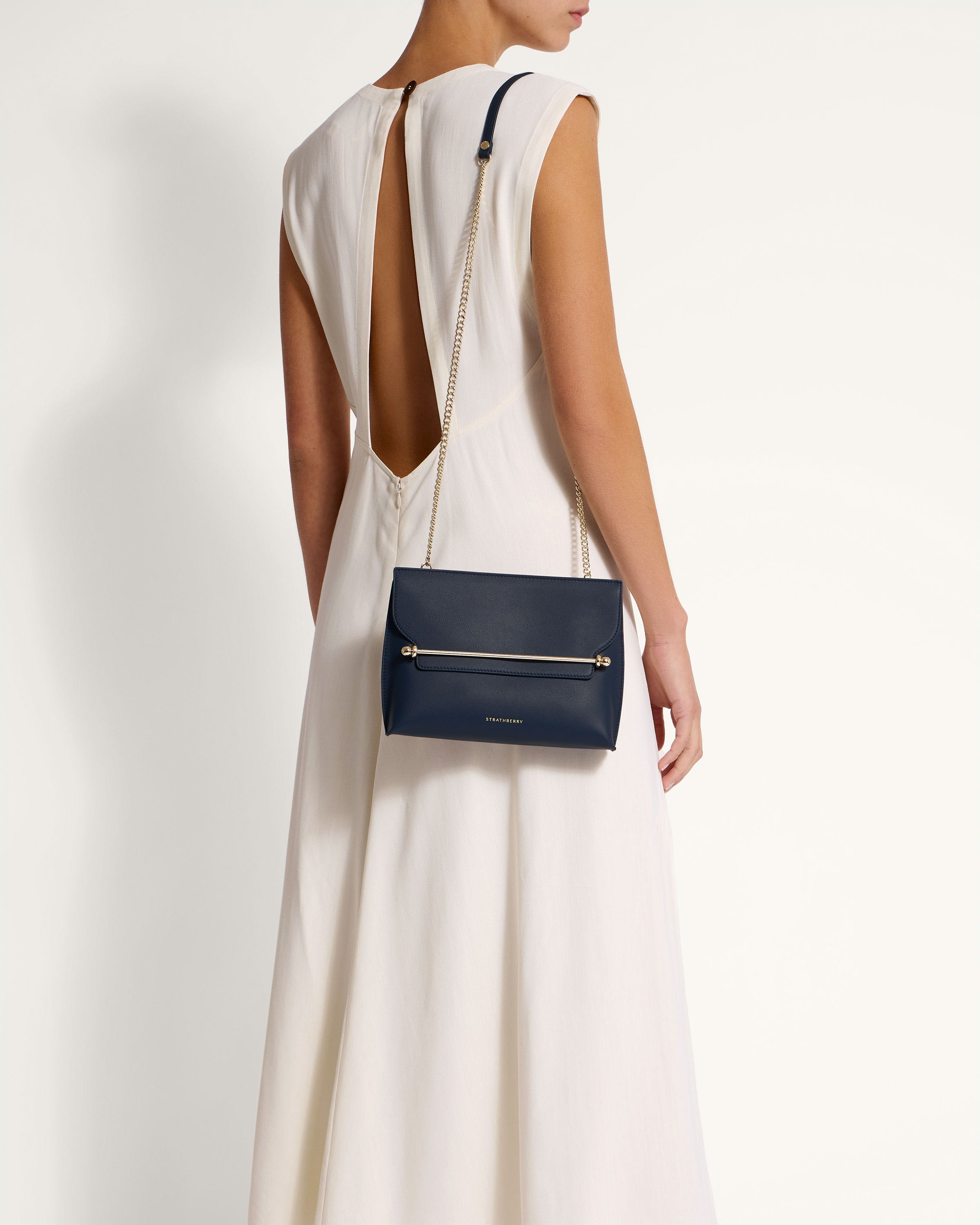 A woman in a white dress holding a blue purse