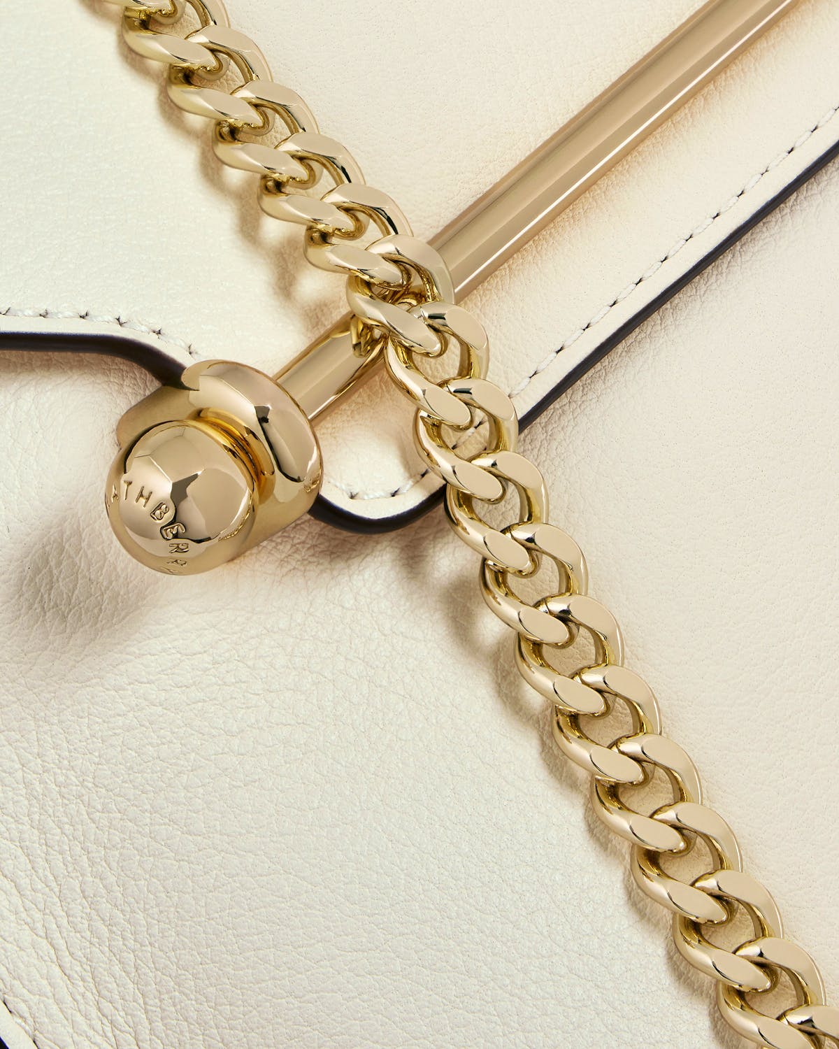 Strathberry vanilla leather bag close-up of gold bar closure and chain
