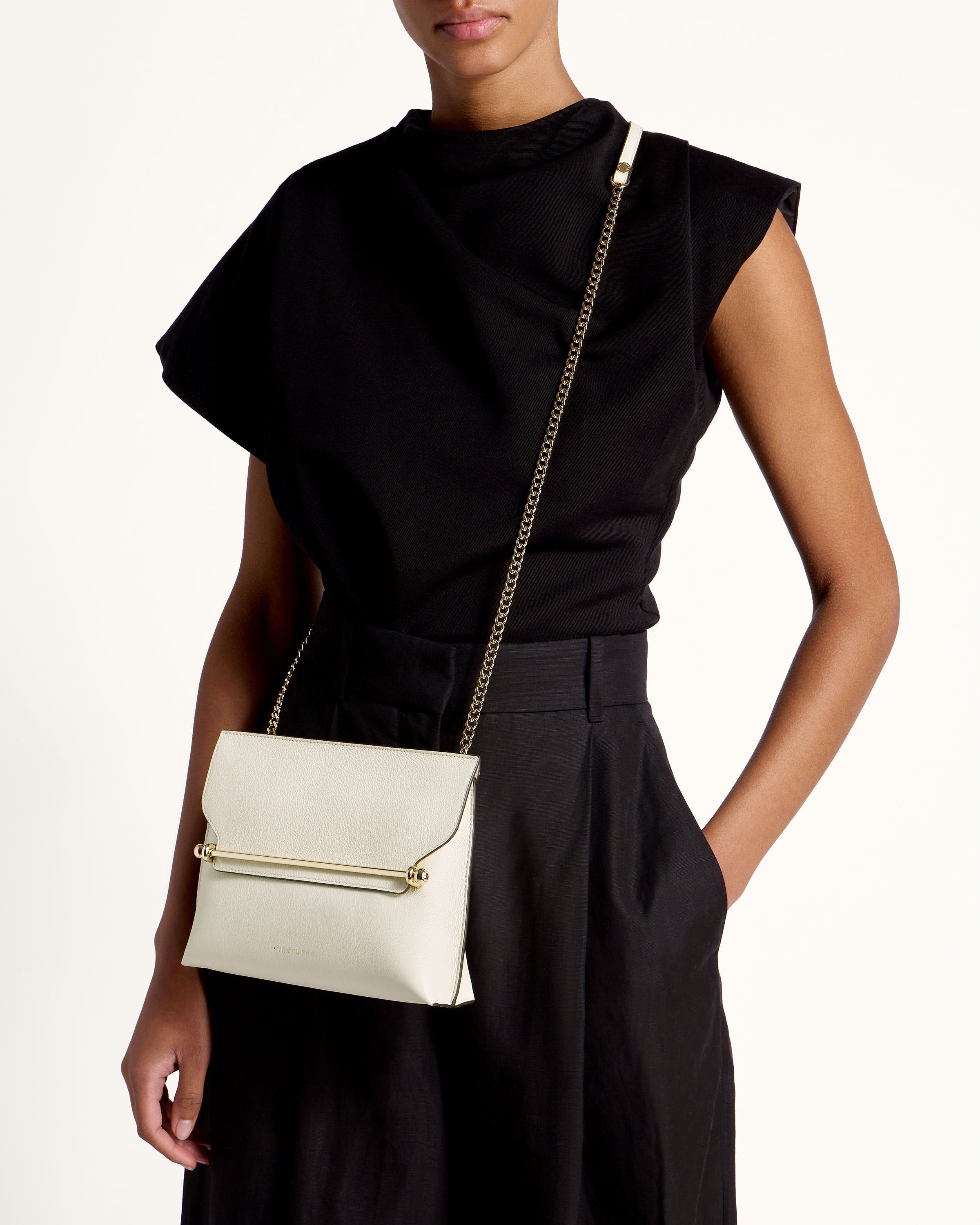 A woman in a black dress holding a white purse