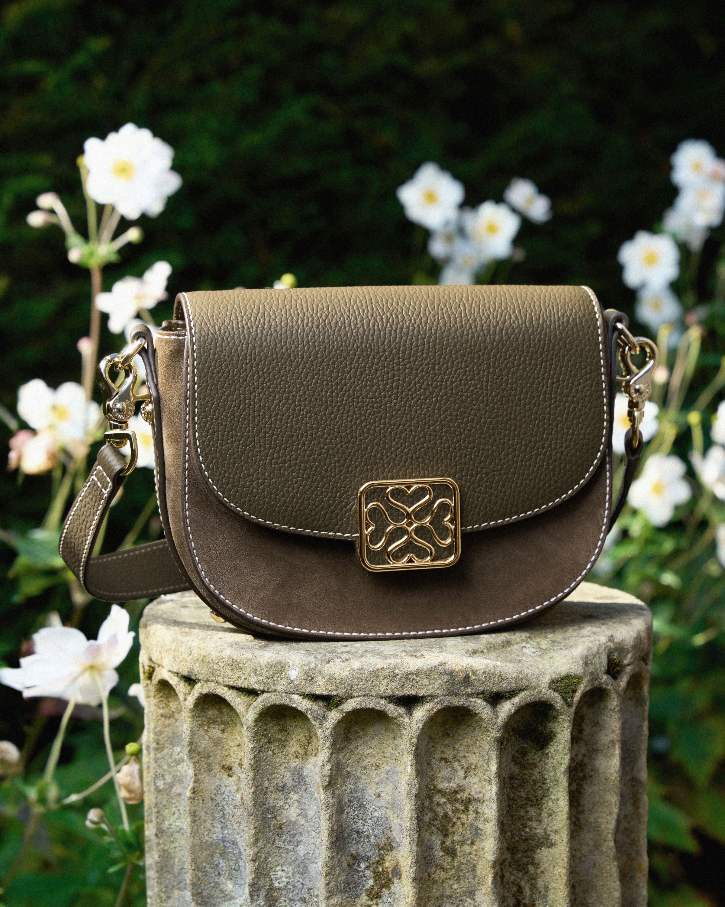 A brown purse sitting on top of a cement pillar