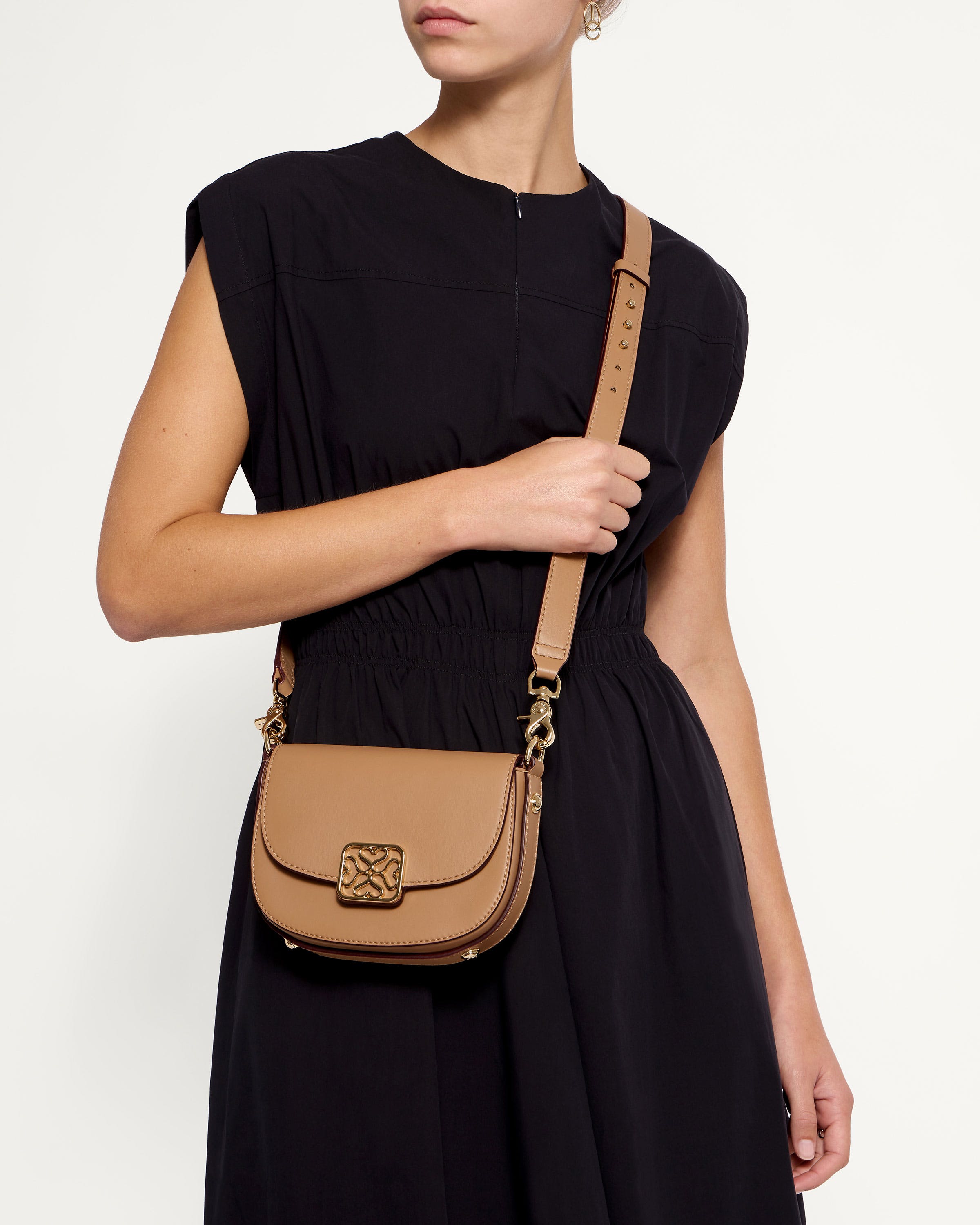 A woman in a black dress holding a tan purse