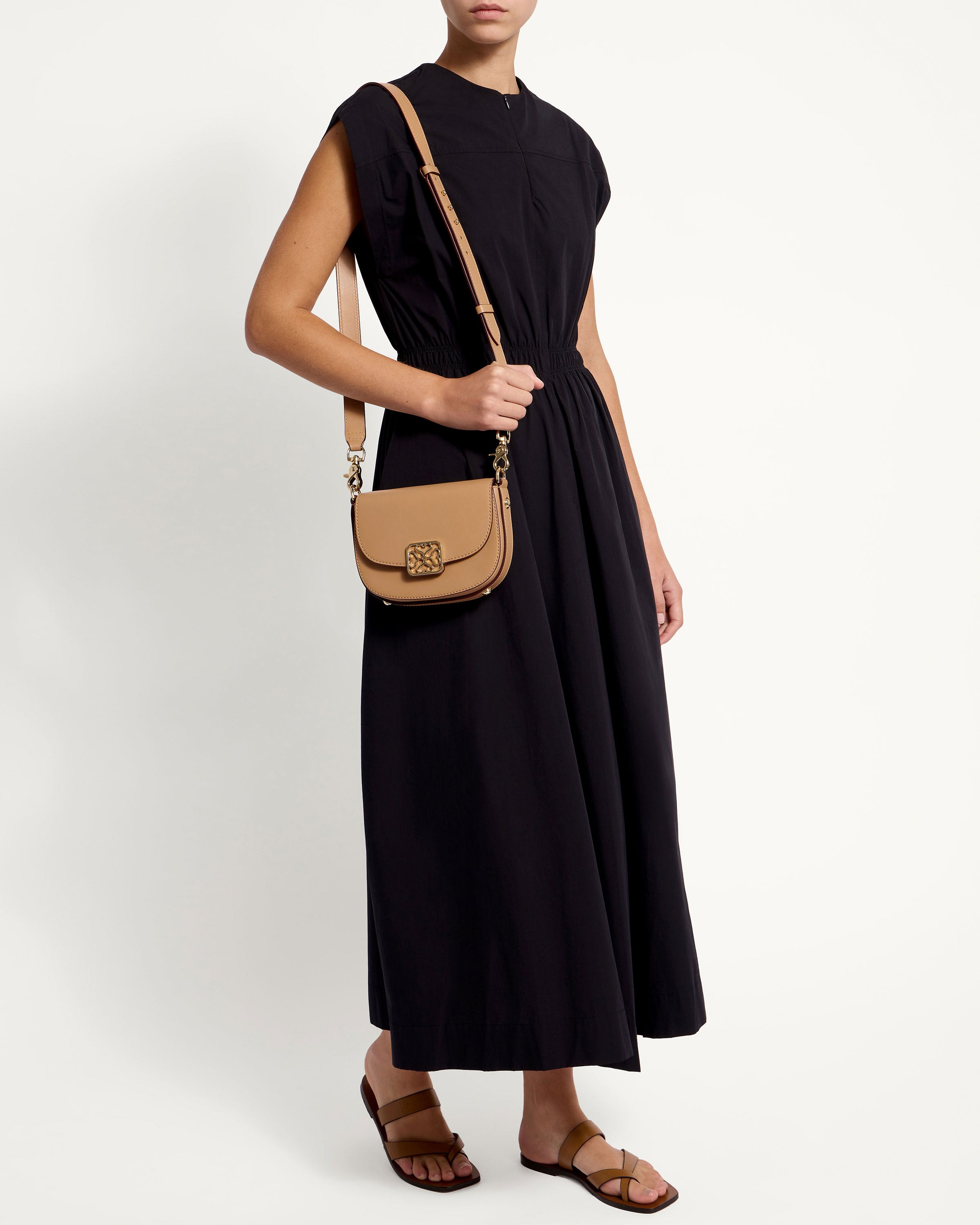 A woman in a black dress holding a tan purse