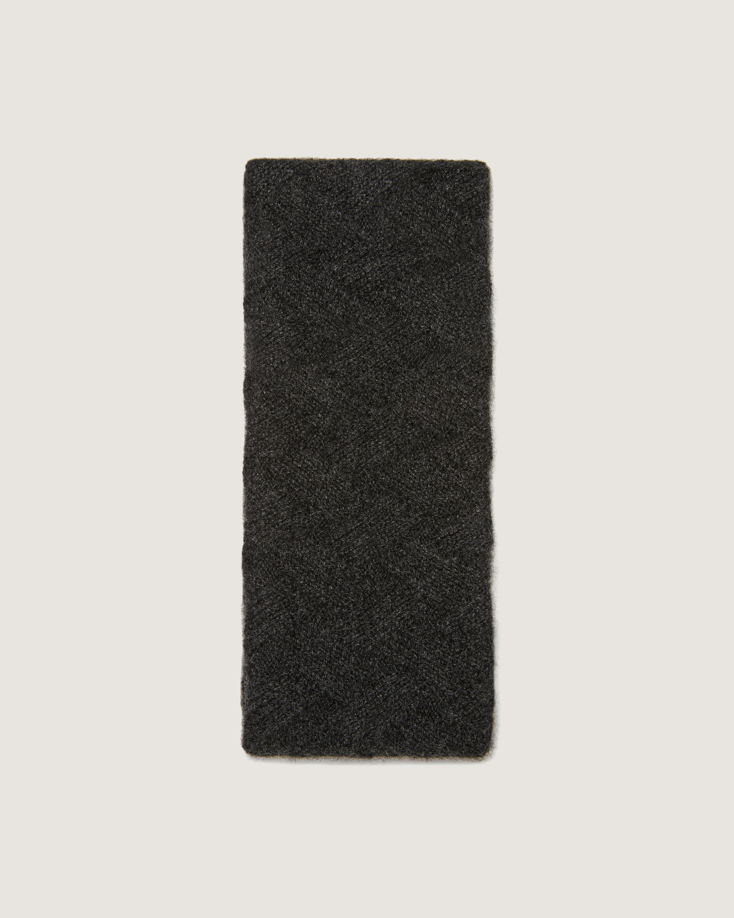 A piece of black wool sitting on top of a white wall