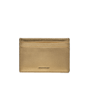 A gold card case on a green background