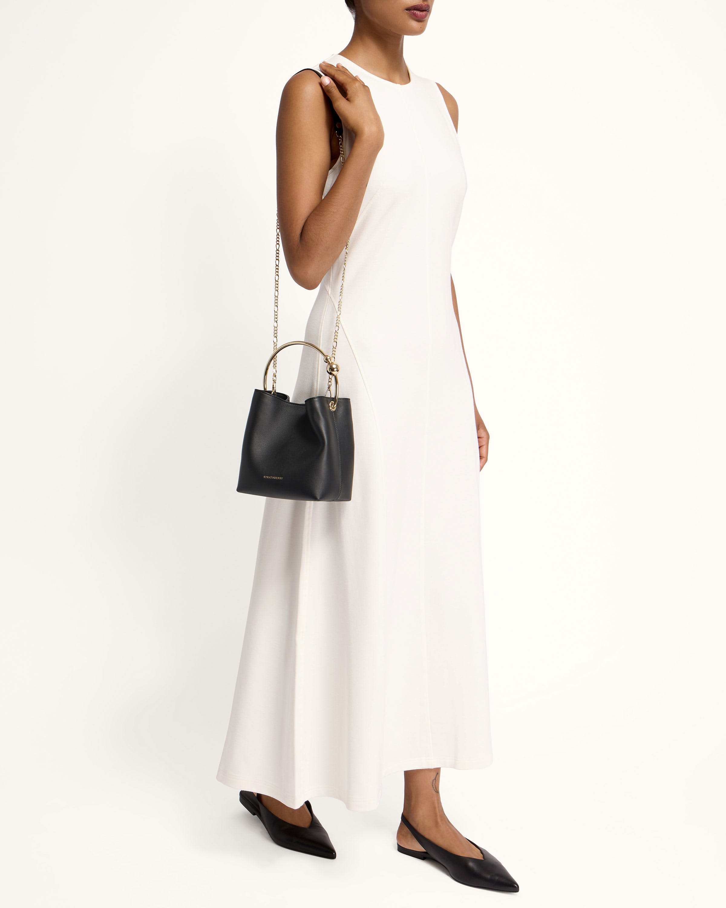 A woman in a white dress holding a black purse