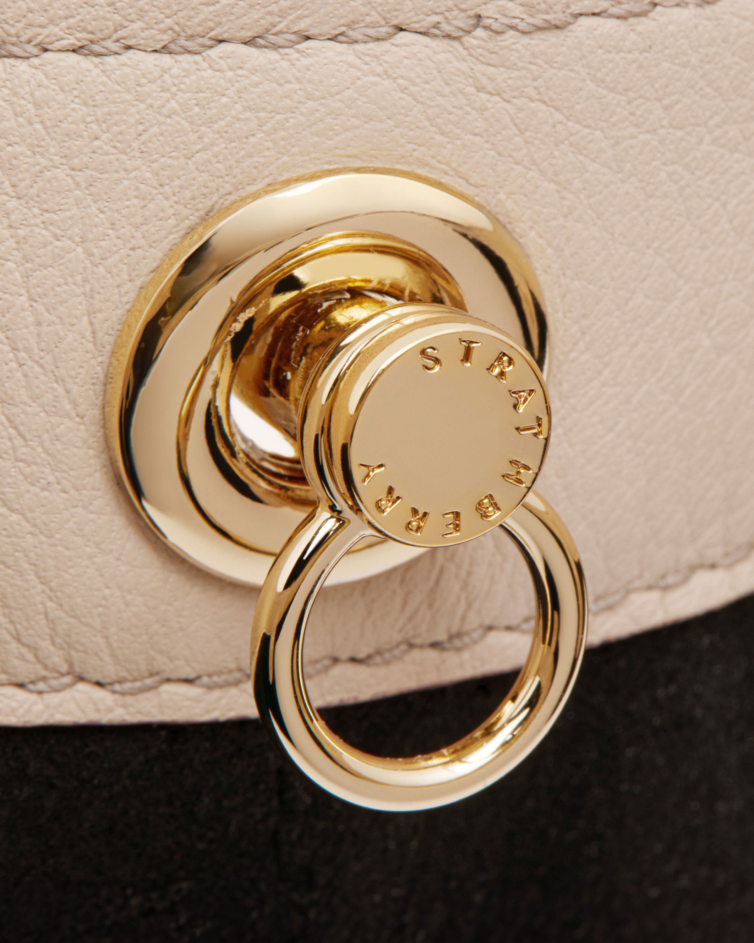 A white purse with a gold ring handle