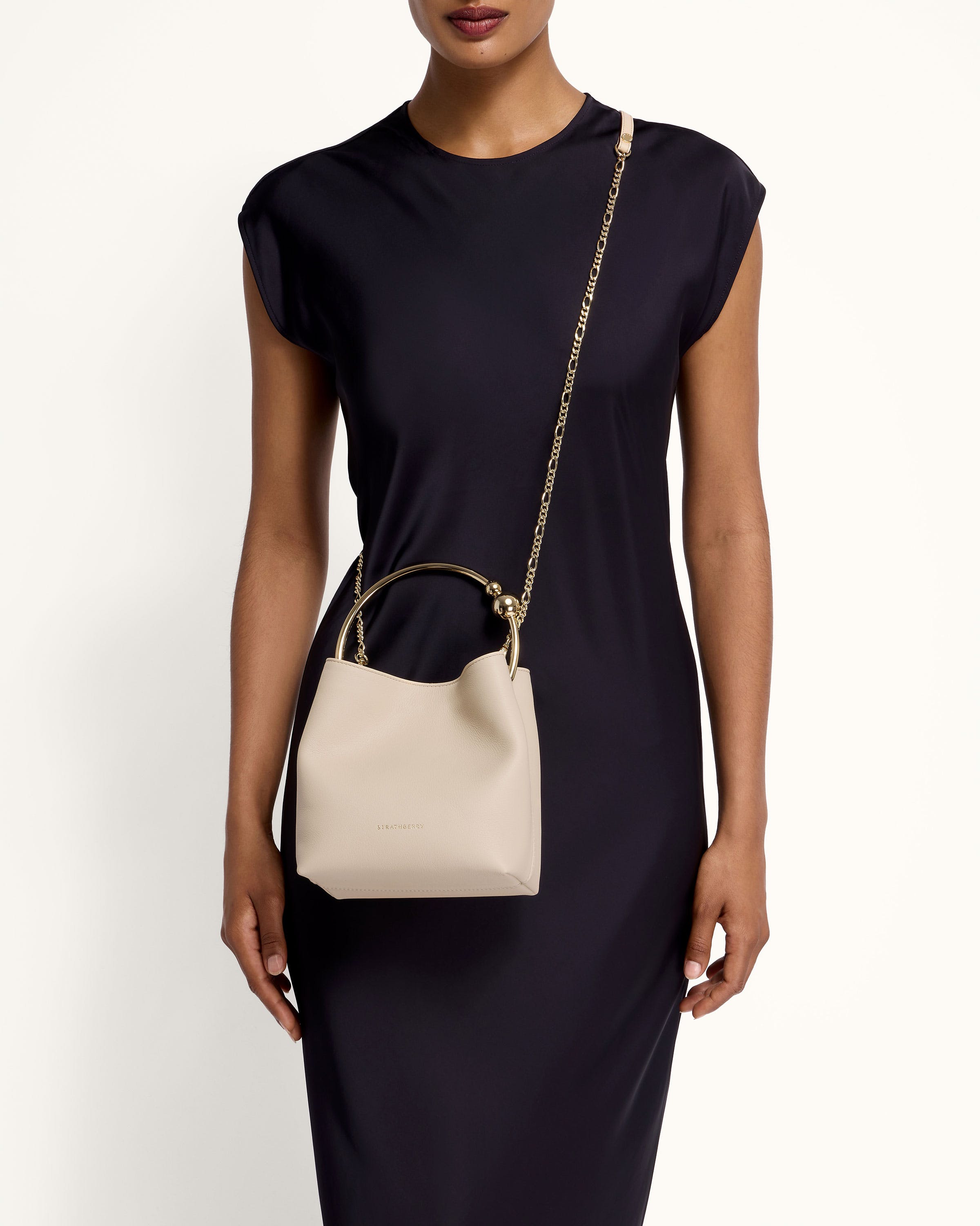 A woman in a black dress holding a white purse